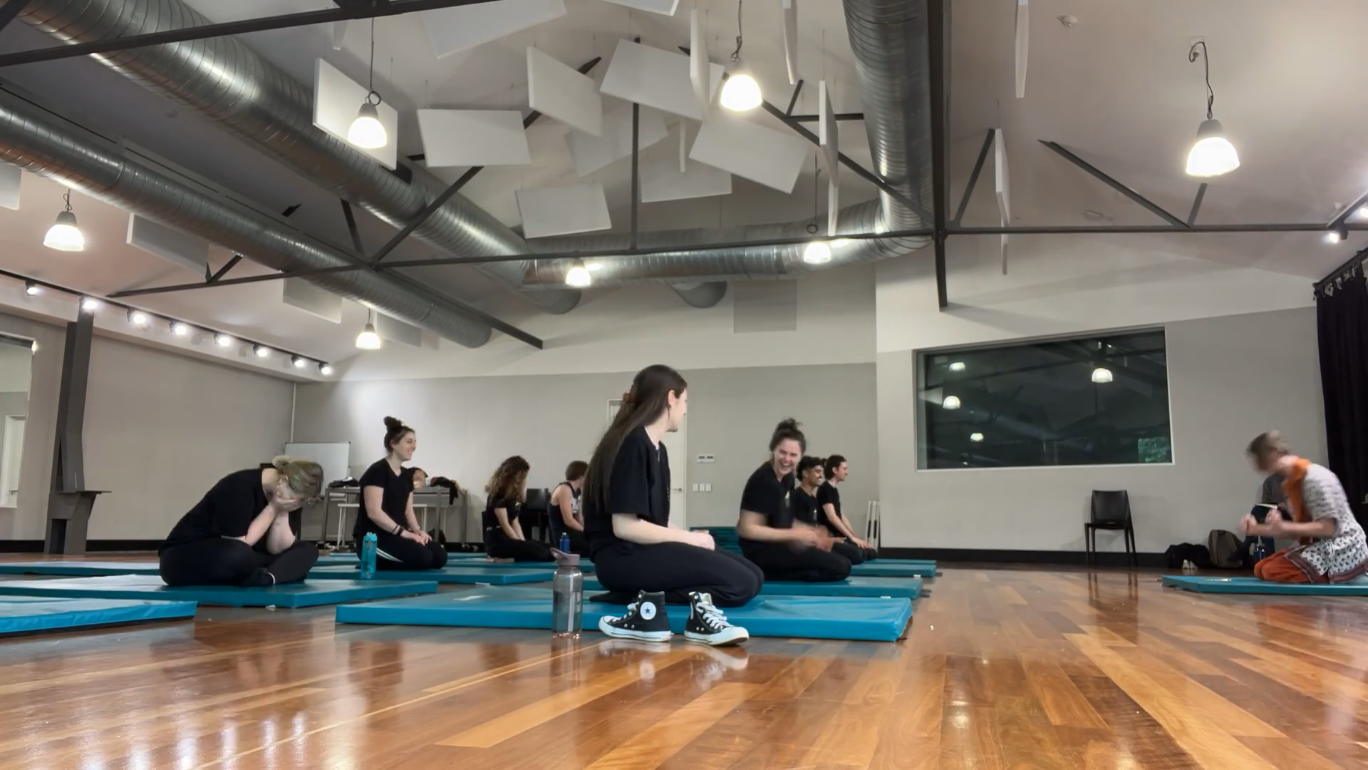 a group of people sitting on blue mats in a gym