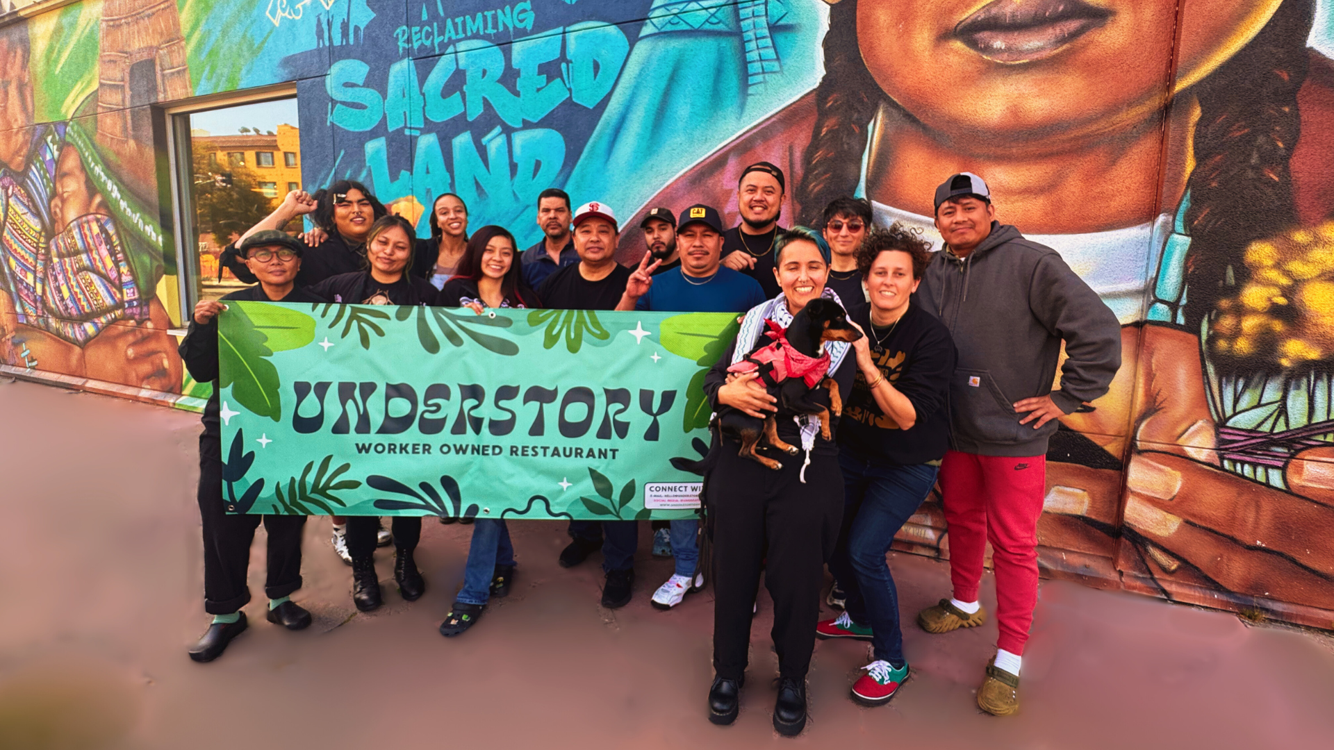 Understory workers standing in front of a mural of a man holding a banner