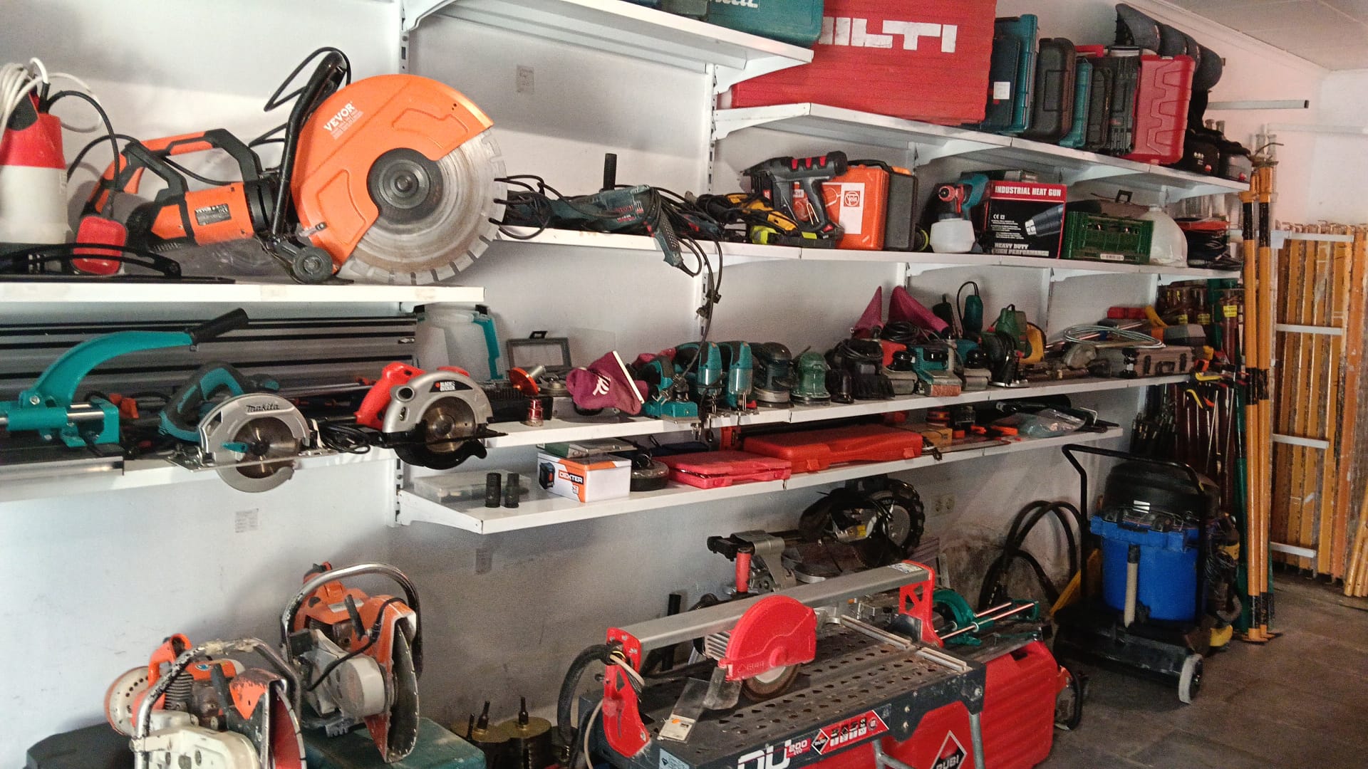 Workshop shelves organized with power tools, circular saws, and construction equipment for professional use.