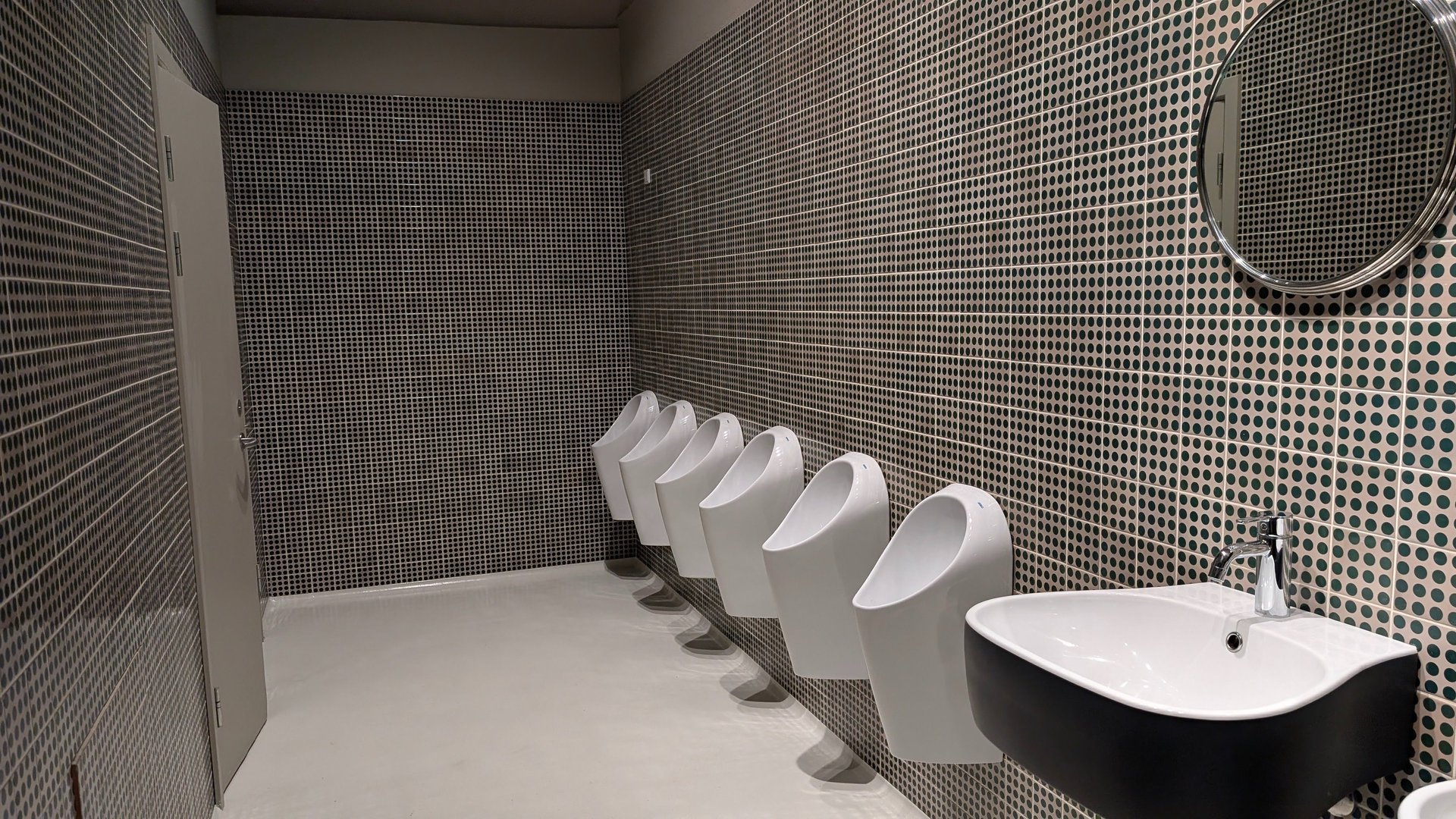Modern unisex restroom interior—minimalist design, open space, six urinals visible