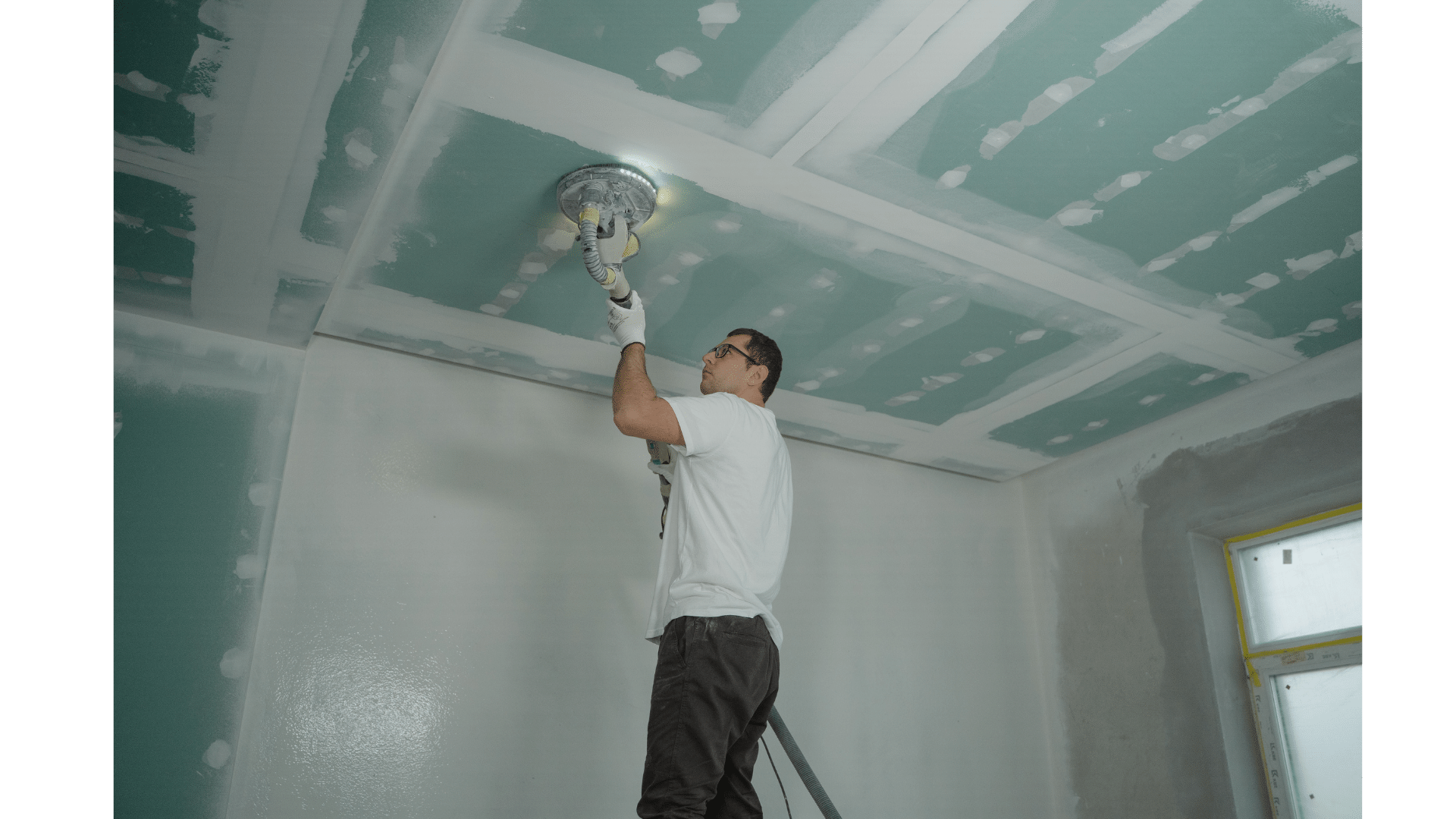 a man is painting a ceiling with a ceiling fan