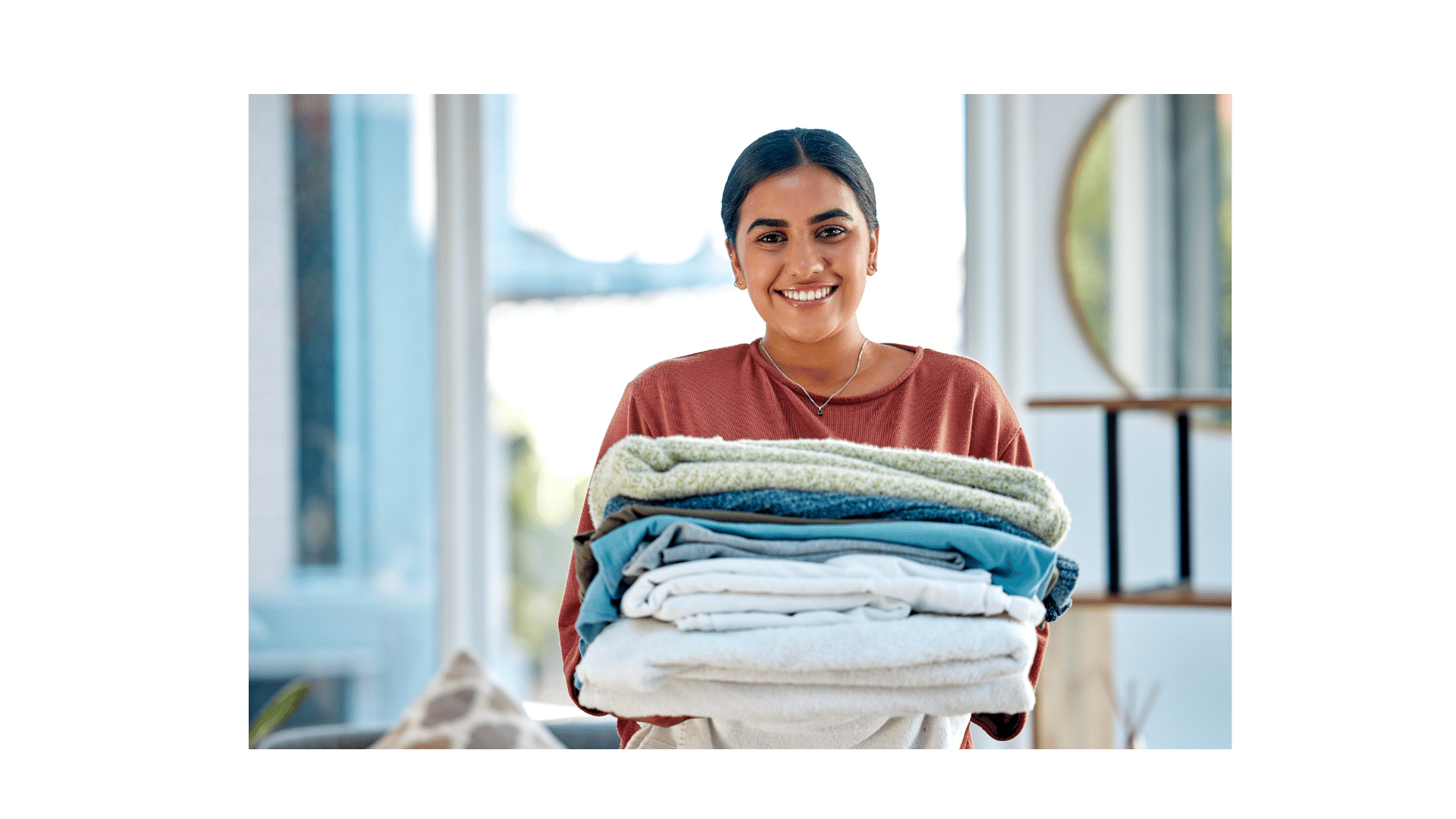 a woman holding a stack of folded towels