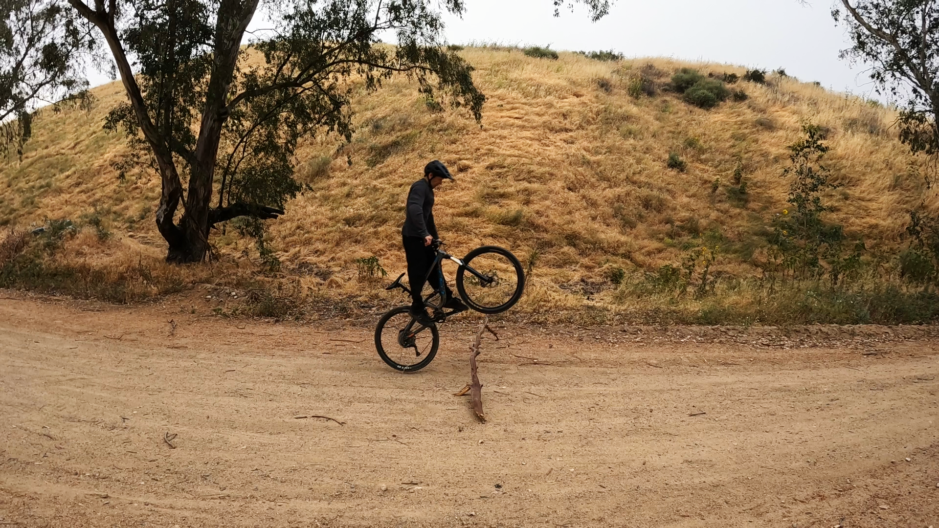 mountain biker lifting front wheel to bunnyhop over a log