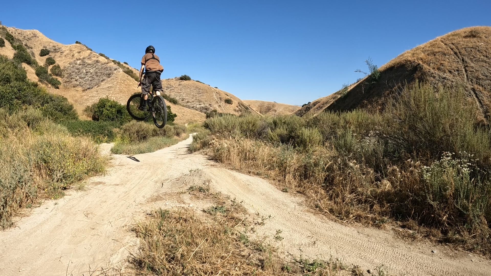 Mountain biker hitting a jump on a mountain bike trail at Hulda Crooks park in loma linda