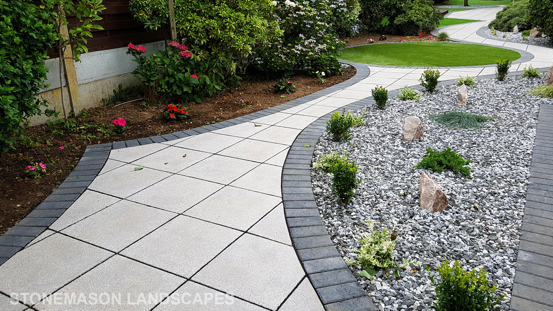 Patio with custom stone circle with aggregates and paving weaving through adventurous garden design