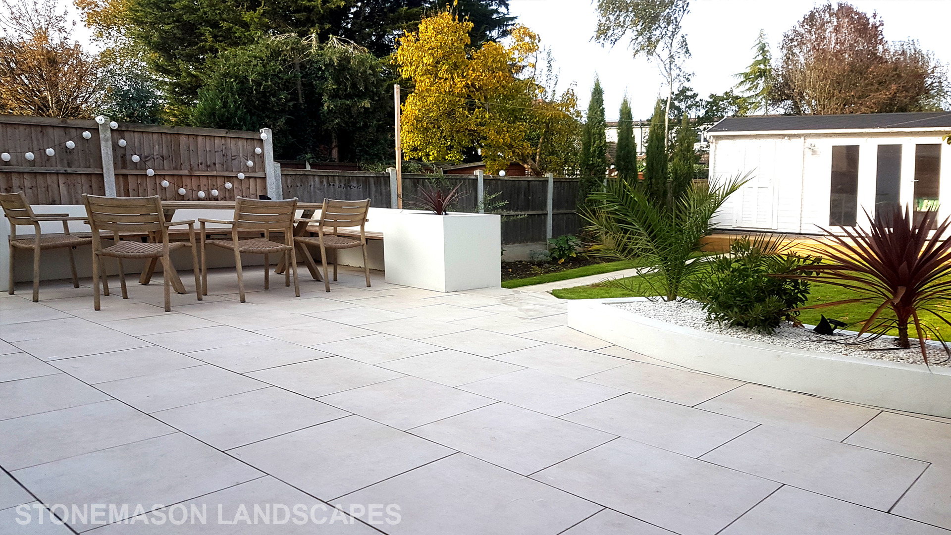 Modern chic raised porcelain patio with white rendered walls and planters
