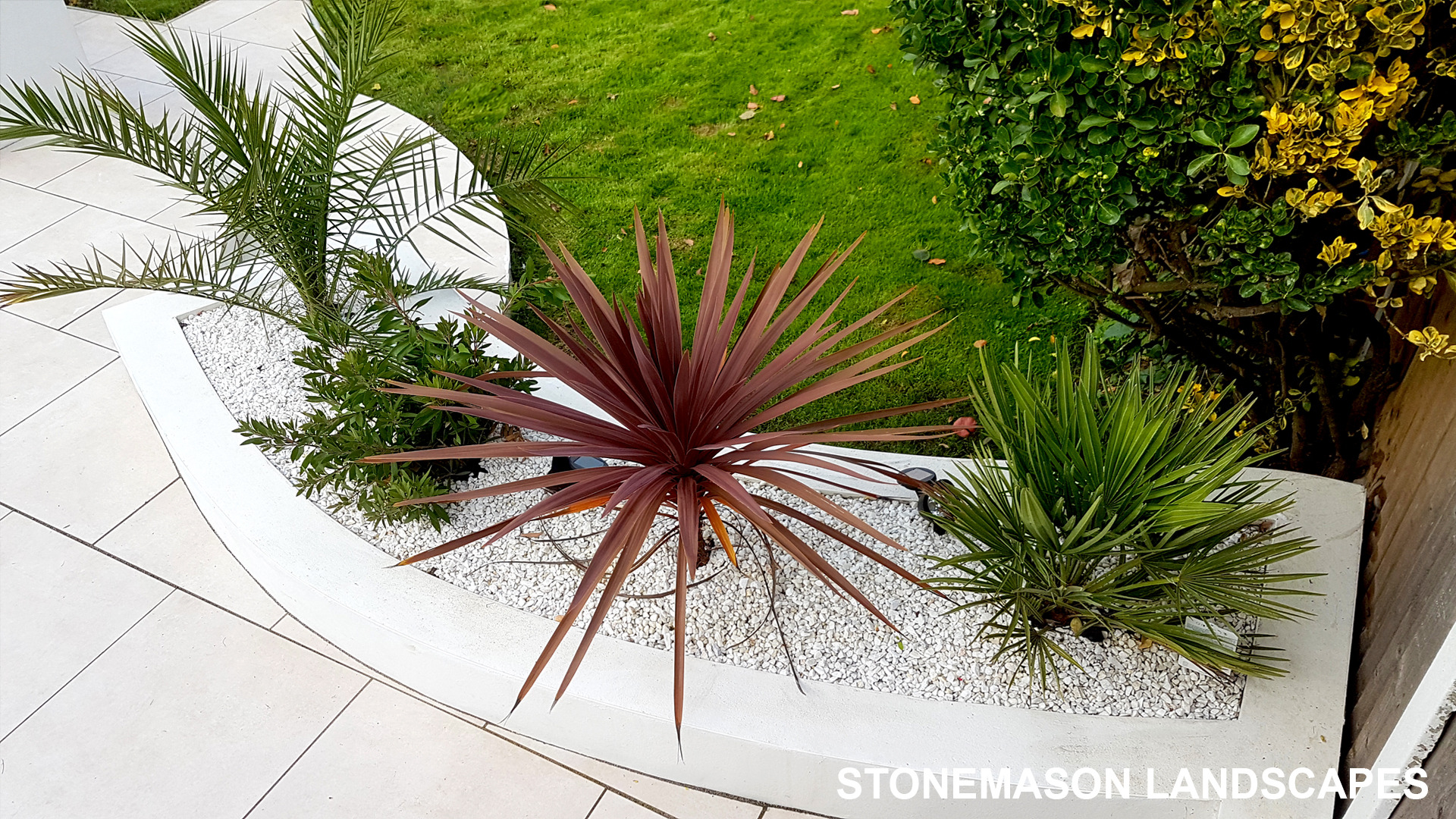 Modern chic raised porcelain patio with white rendered walls and planters