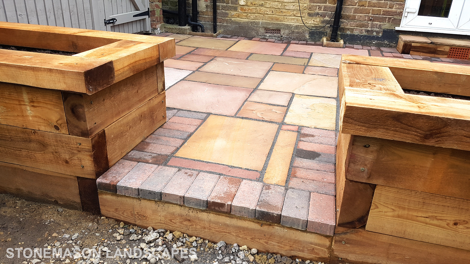 Colourful sandstone patio with raised wooden timber planter seating