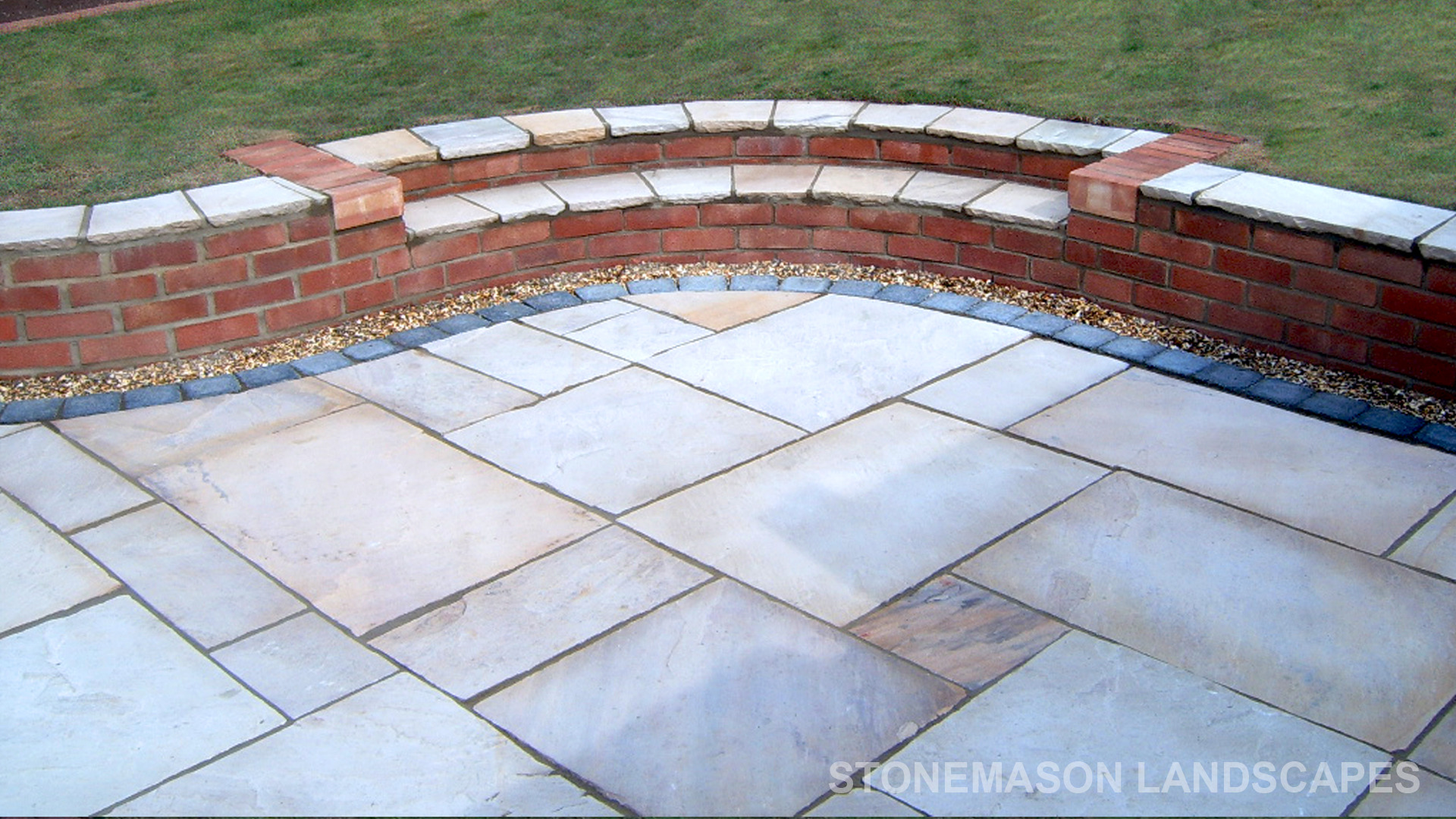 Multi-level sunken sandstone patio step up to lawn with retaining wall