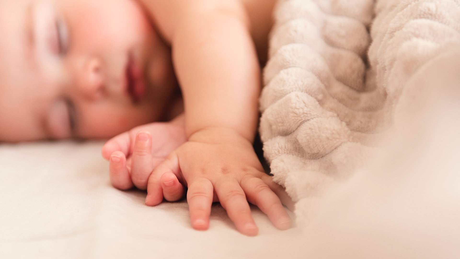 a baby is laying on a bed with a blanket
