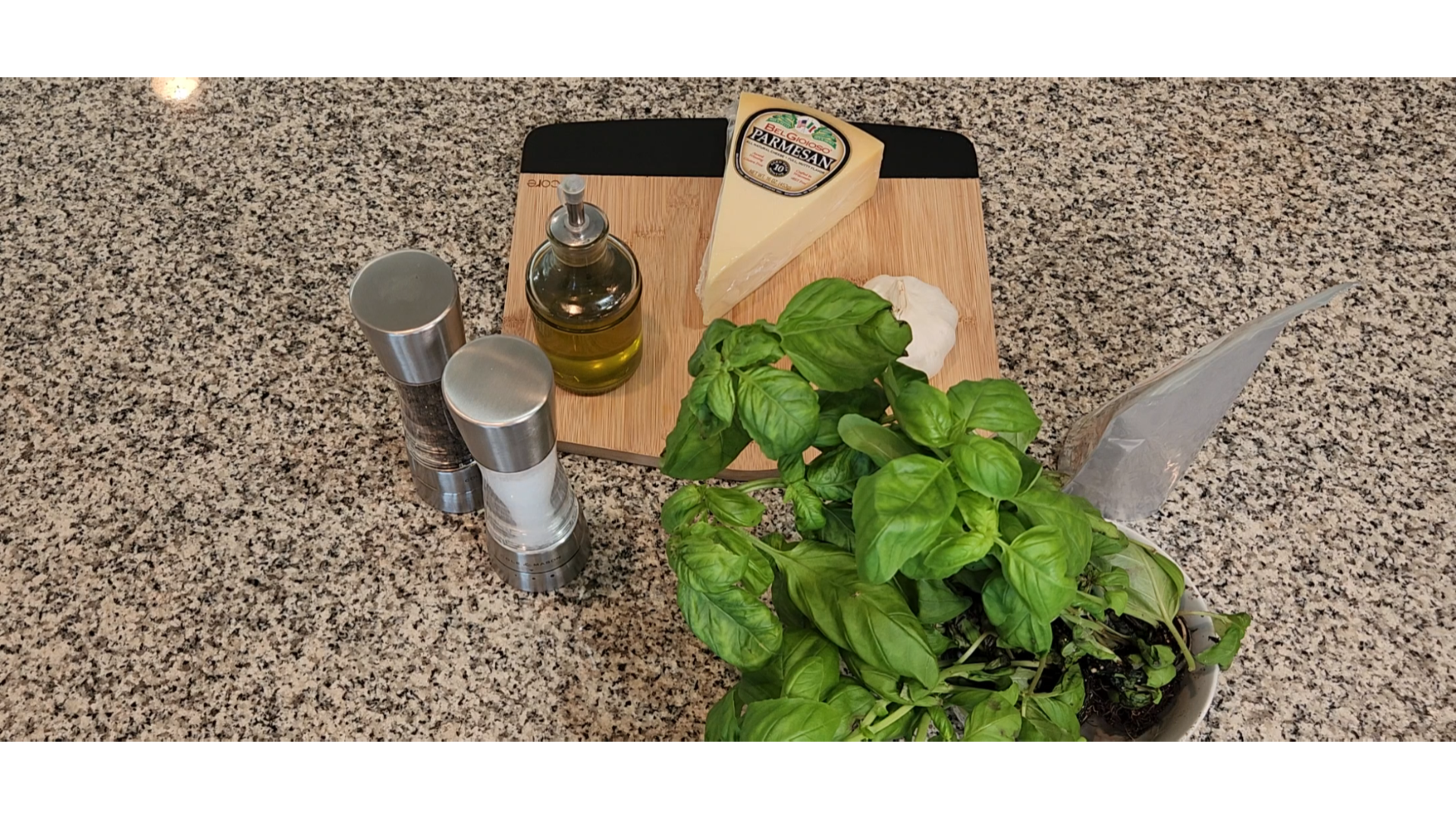 a cutting board on a counter with parmesan cheese, salt, pepper, allbaca olive oil and garlic