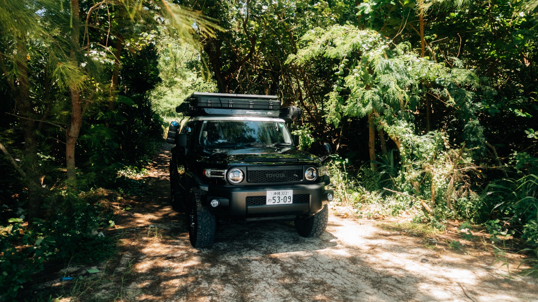 Toyota FJ Cruiser parked on a sandy trail surrounded by lush greenery in Okinawa. | Evertrail Okinawa