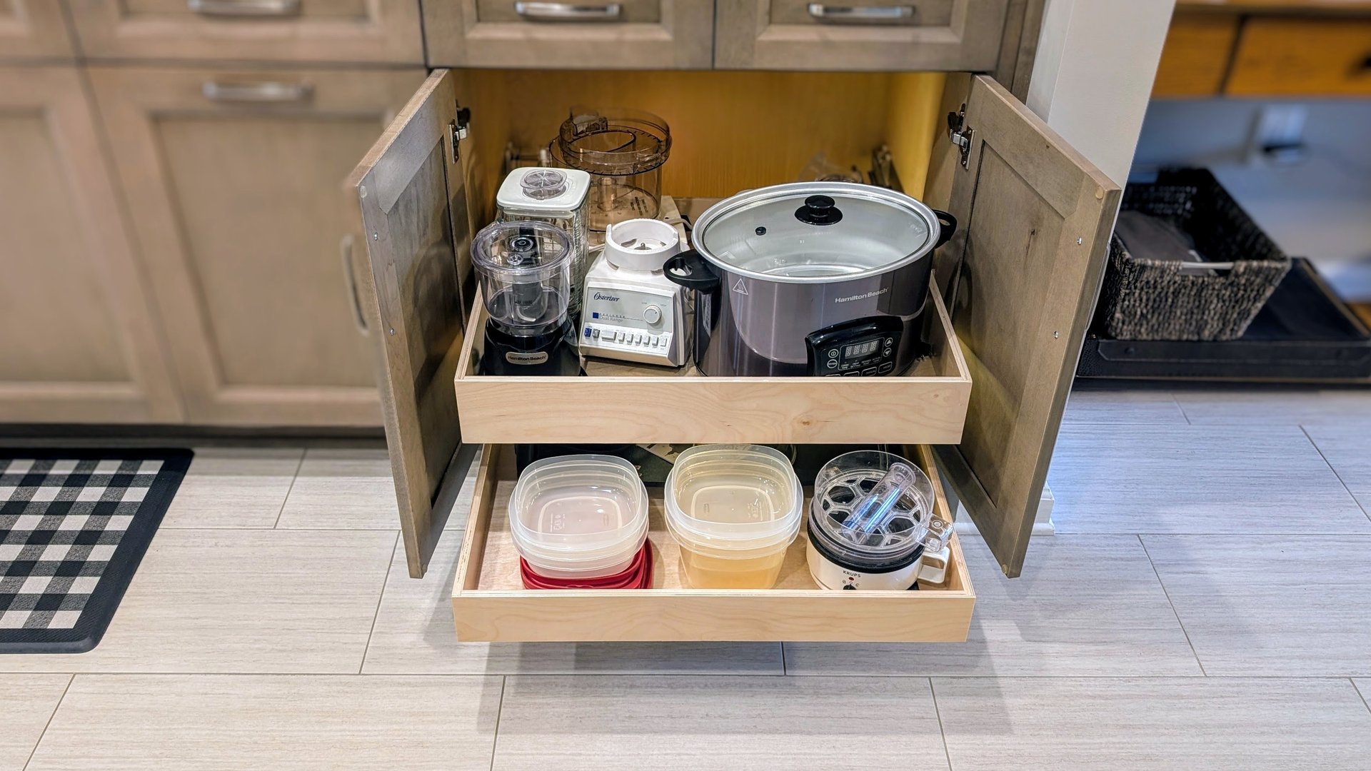 A kitchen cabinet with custom slide out shelves that are fully loaded with kitchen items.