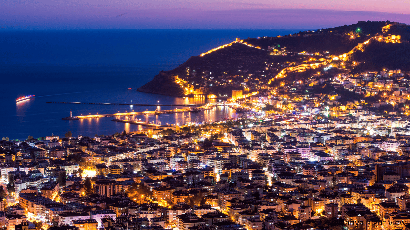 Stunning night view of Alanya city lights and the historical castle by the sea