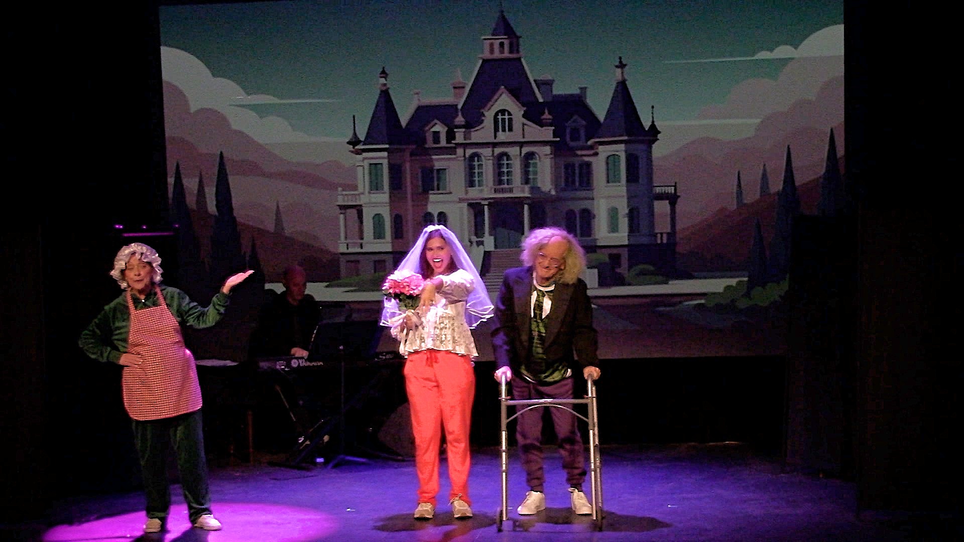 A theatrical comedy performance on stage featuring actors in costumes with a haunted mansion backdrop.