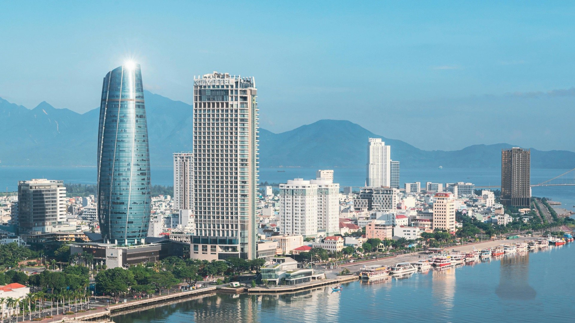 Da Nang city skyline with mountains, river, boats and buildings during the day
