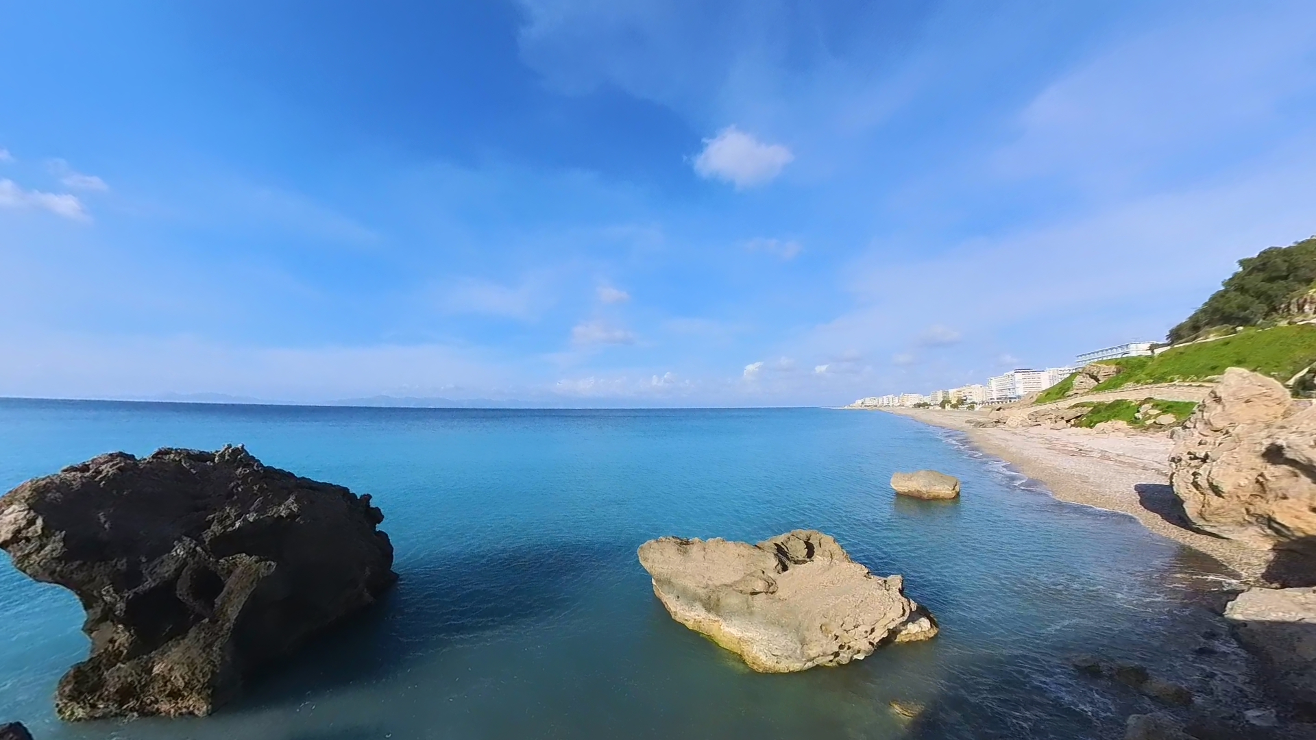 Scenic coastal view of Rhodes, Greece with turquoise Mediterranean water and rocky beach.