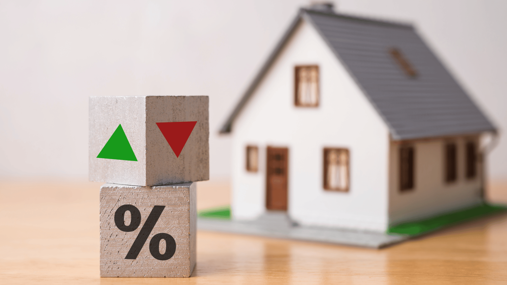 blocks with green and red arrows for interest rates beside tiny house