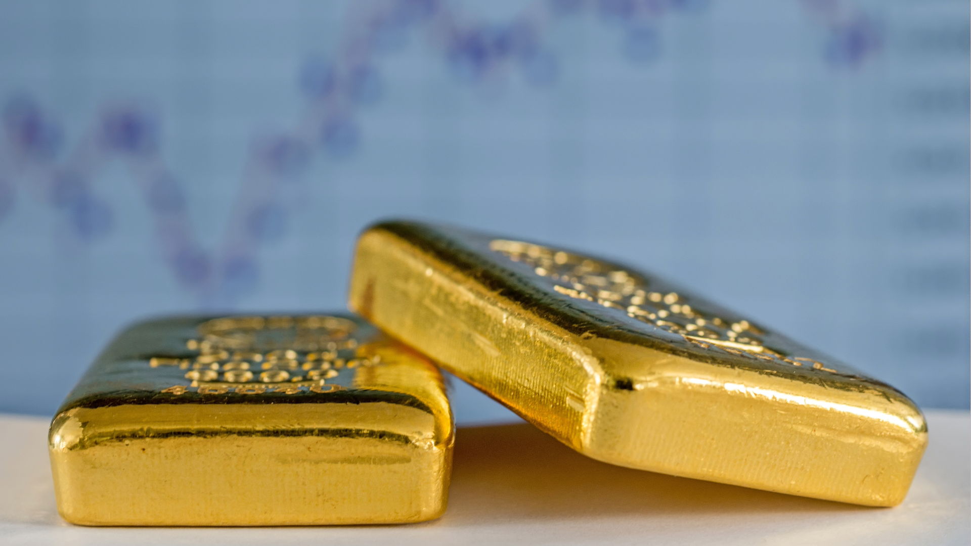 gold bullion bars on flat surface with charts in background