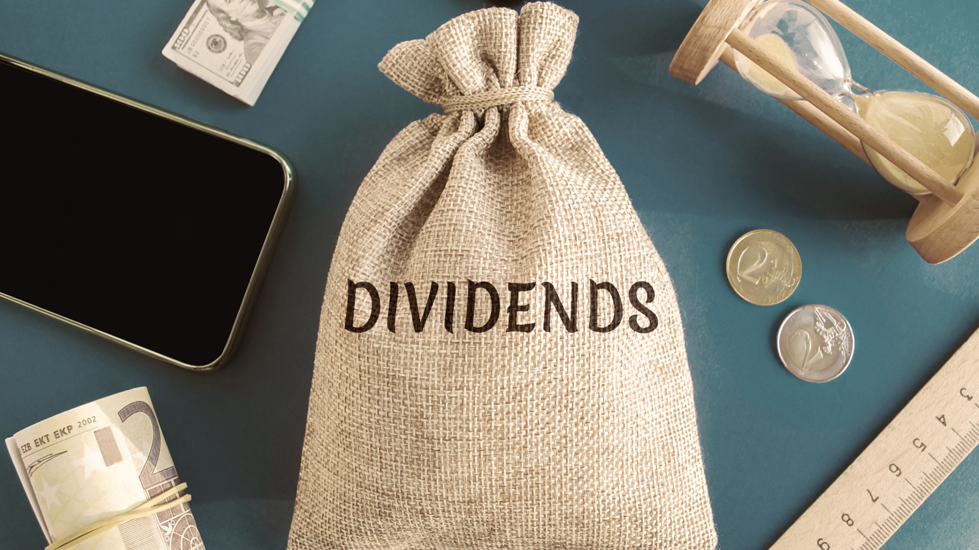 money bag a phone coins and a ruler for dividend growth investing
