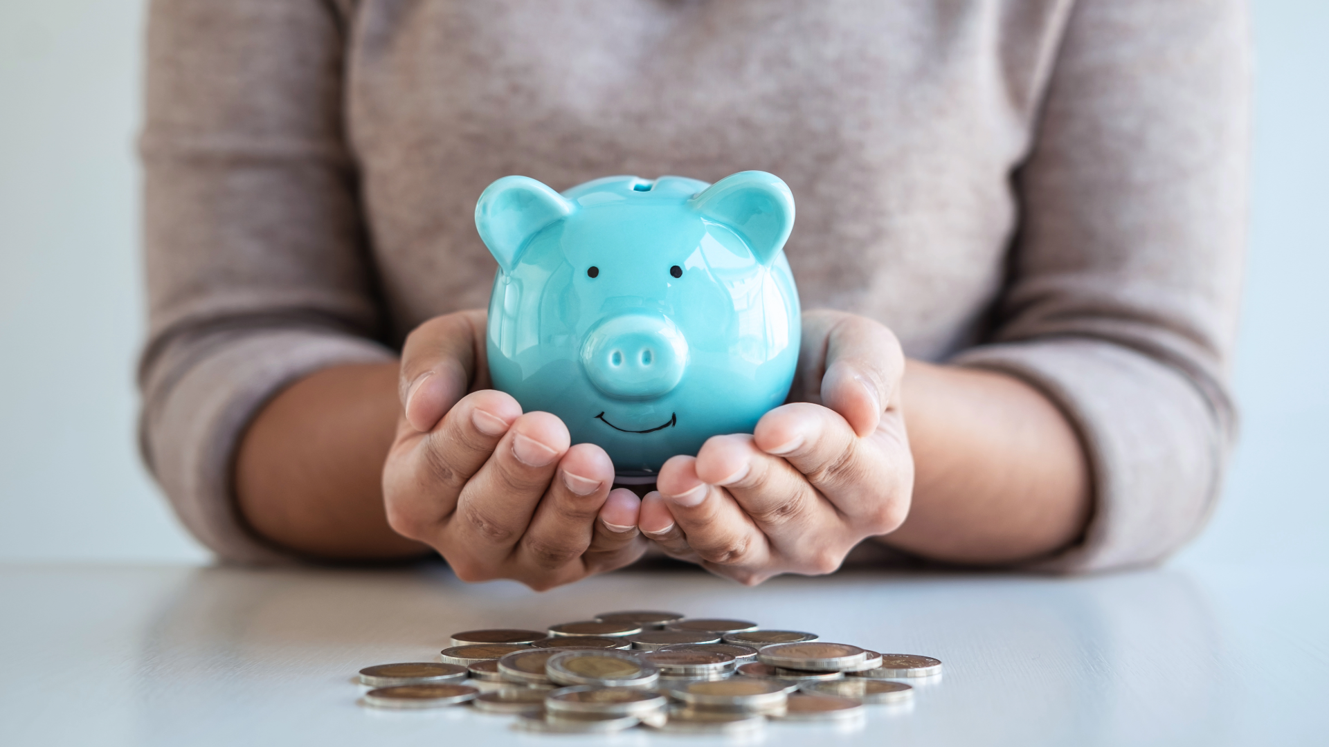 woman holding a piggy bank with coins on the table for retirement