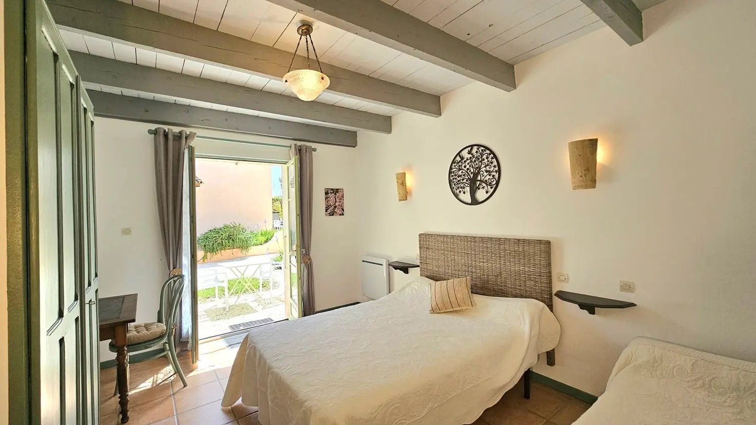 Chambre sauge de la maison d'hôtes la ramade, grand lit vue porte fenêtre extérieur.