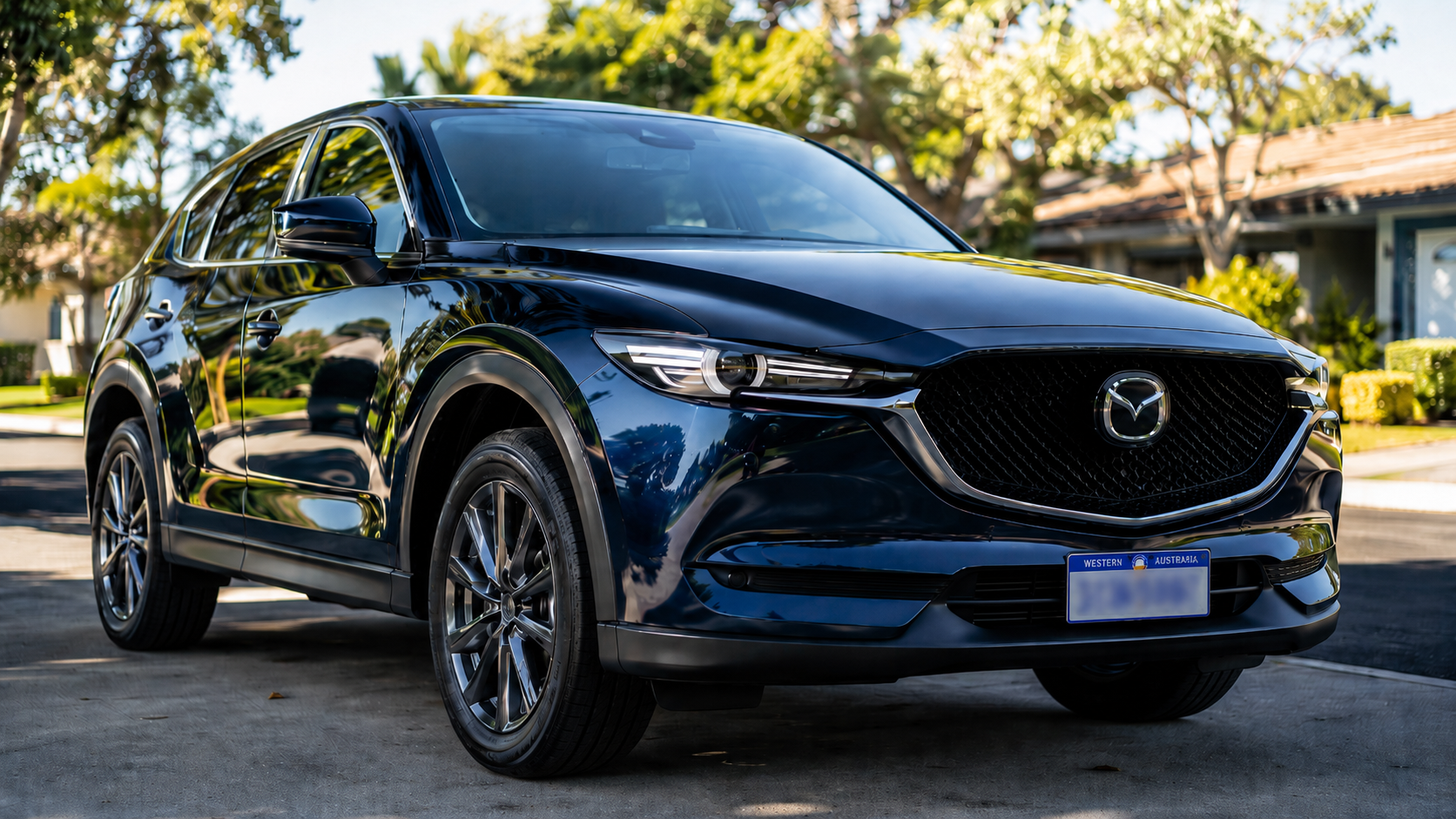 A sleek navy blue Mazda CX-5 SUV parked on a sunny residential driveway after paint correction 