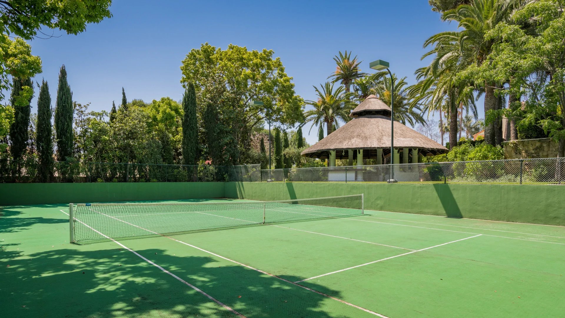 Private tennis court in landscaped Marbella villa grounds
