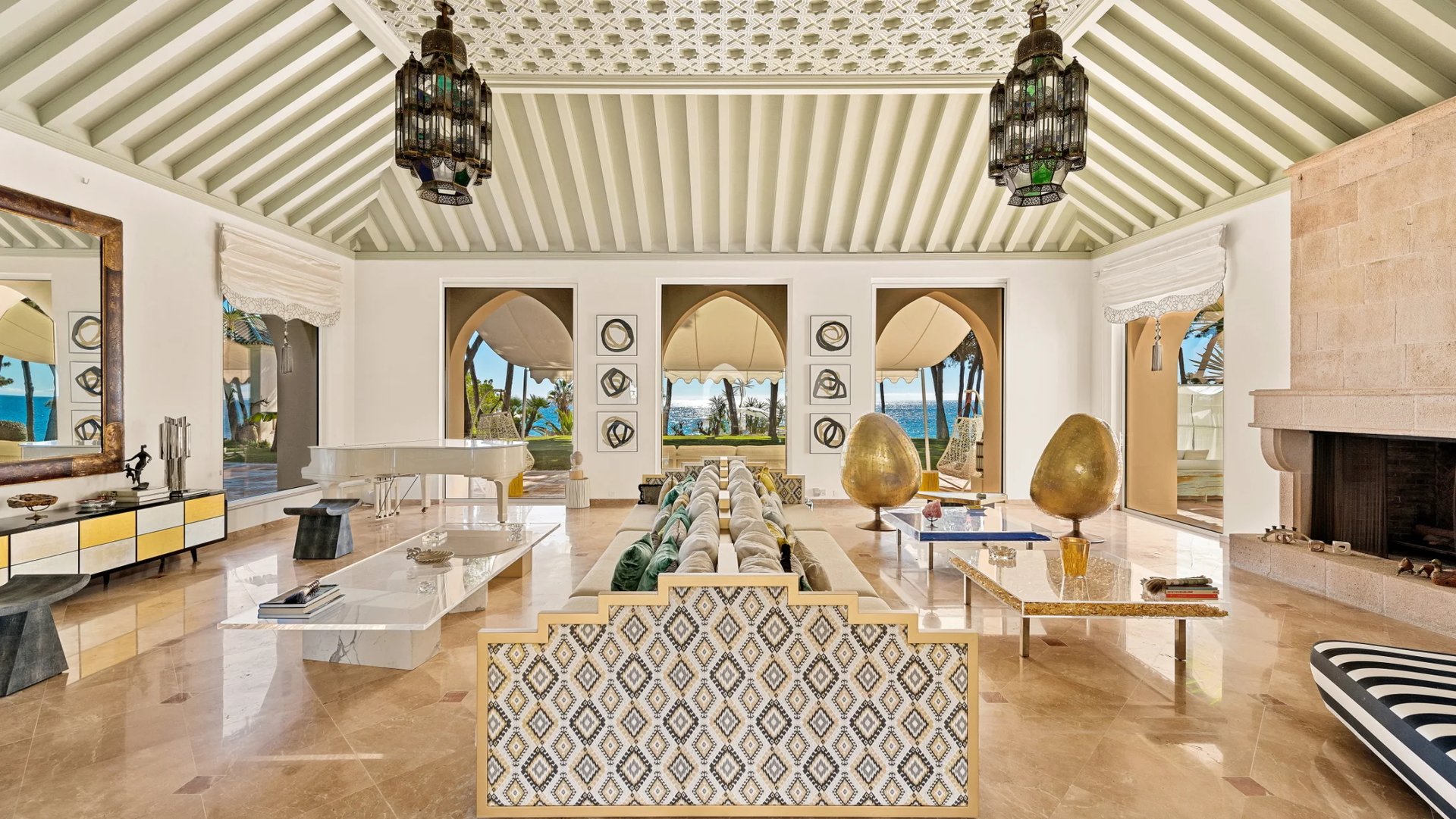 Elegant living room with grand piano, fireplace and arched ocean views