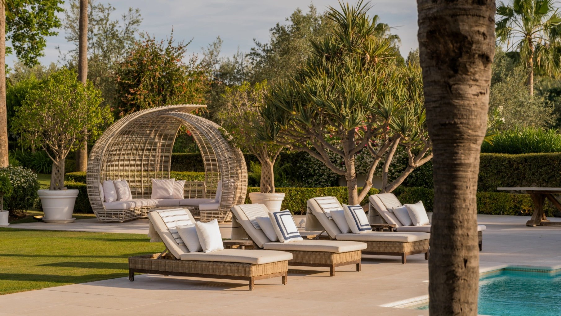 Outdoor loungers surrounded by tropical gardens at Villa El Olivo, Marbella.