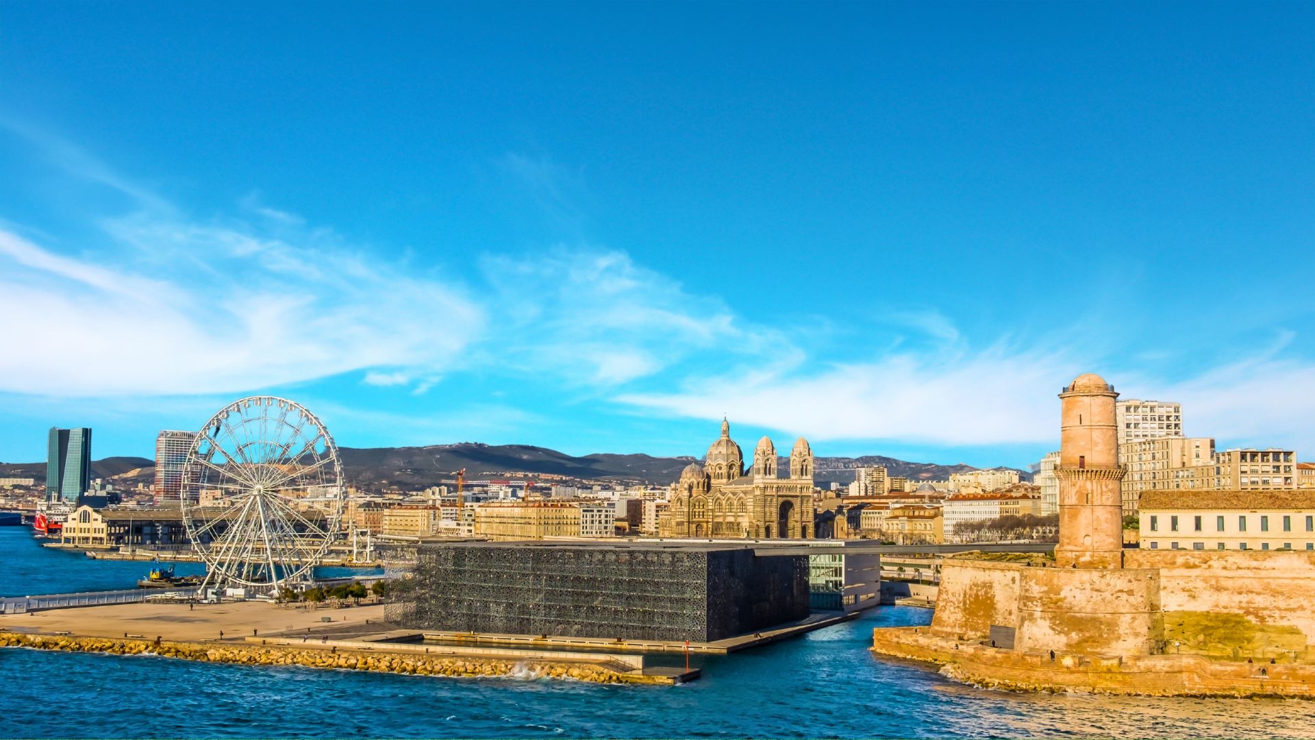 Cidade de Marselha vista do mar, com fortalezas e a grande roda-gigante na chegada ao porto