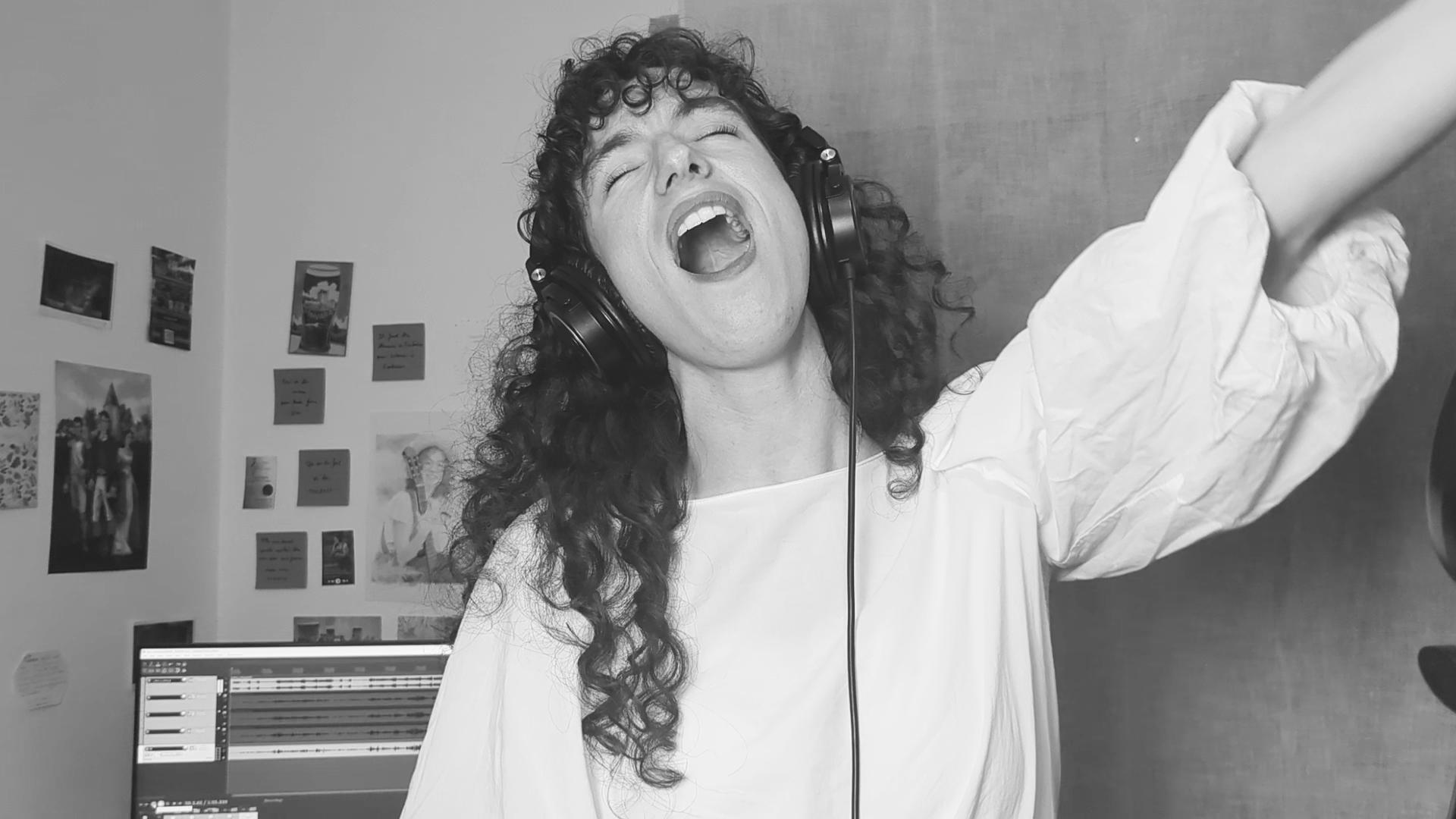photo en noir et  blanc de aude fy en train de chanter avec casque sur les oreilles