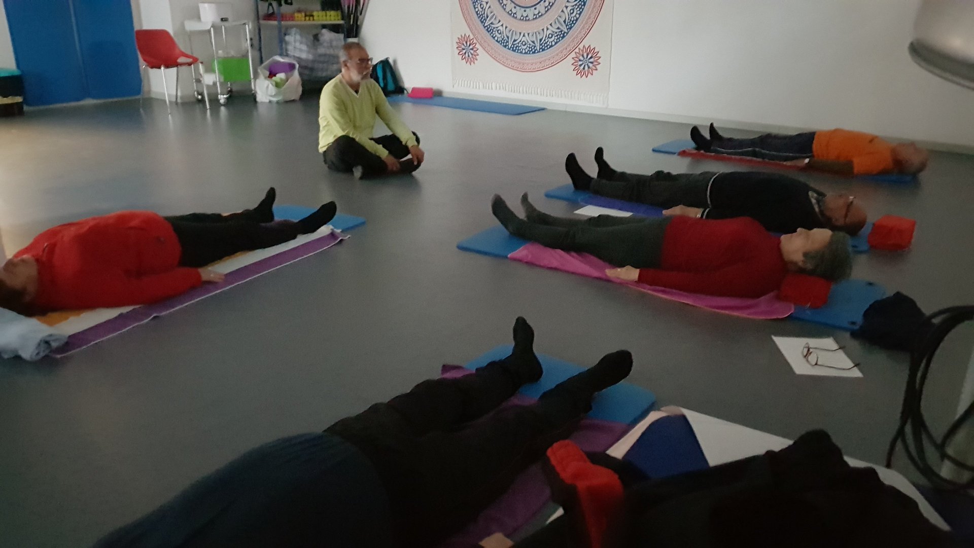 Un grupo de personas está realizando ejercicios de relajación sobre esterillas después de una sesión