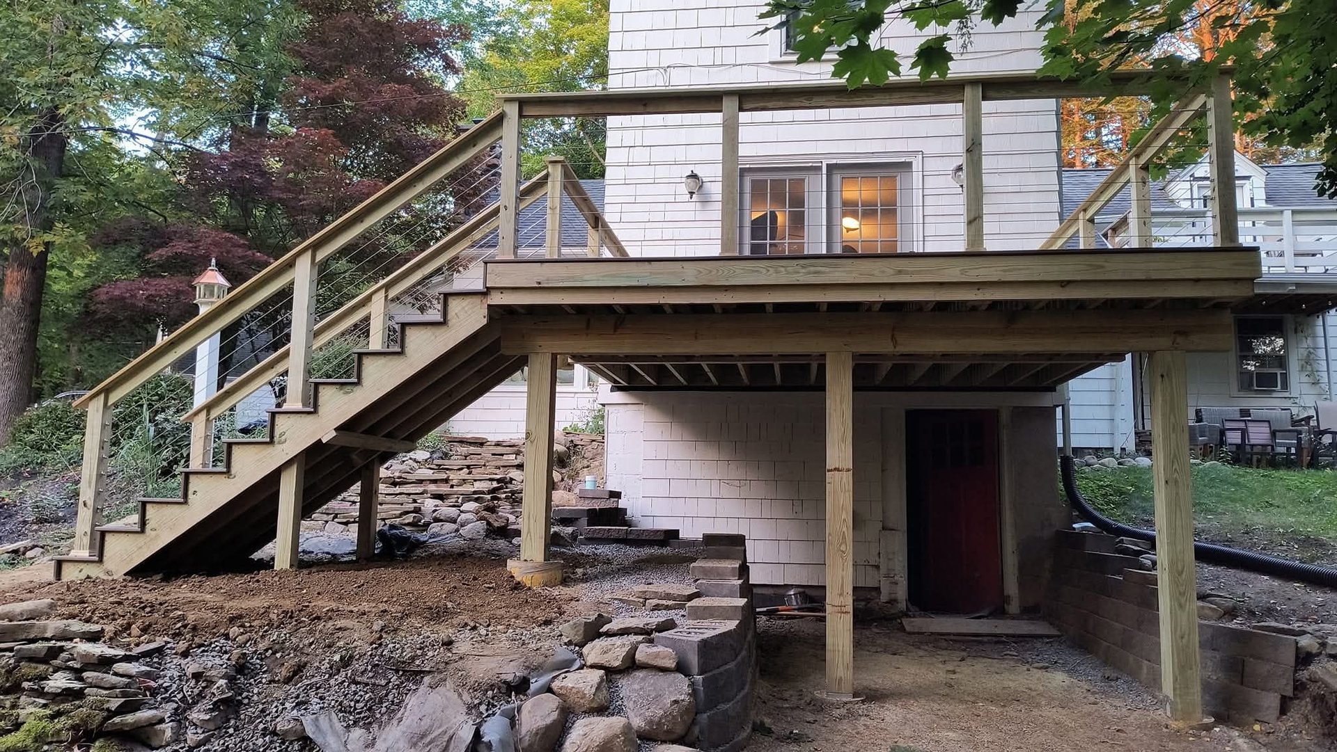Custom wood deck with outdoor seating overlooking a wooded backyard landscape