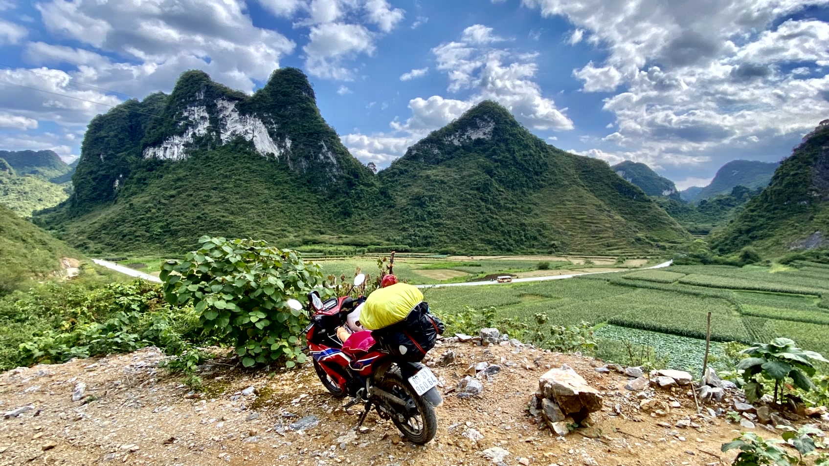 a motorcycle parked on a dirt road near a mountain in Vietnam