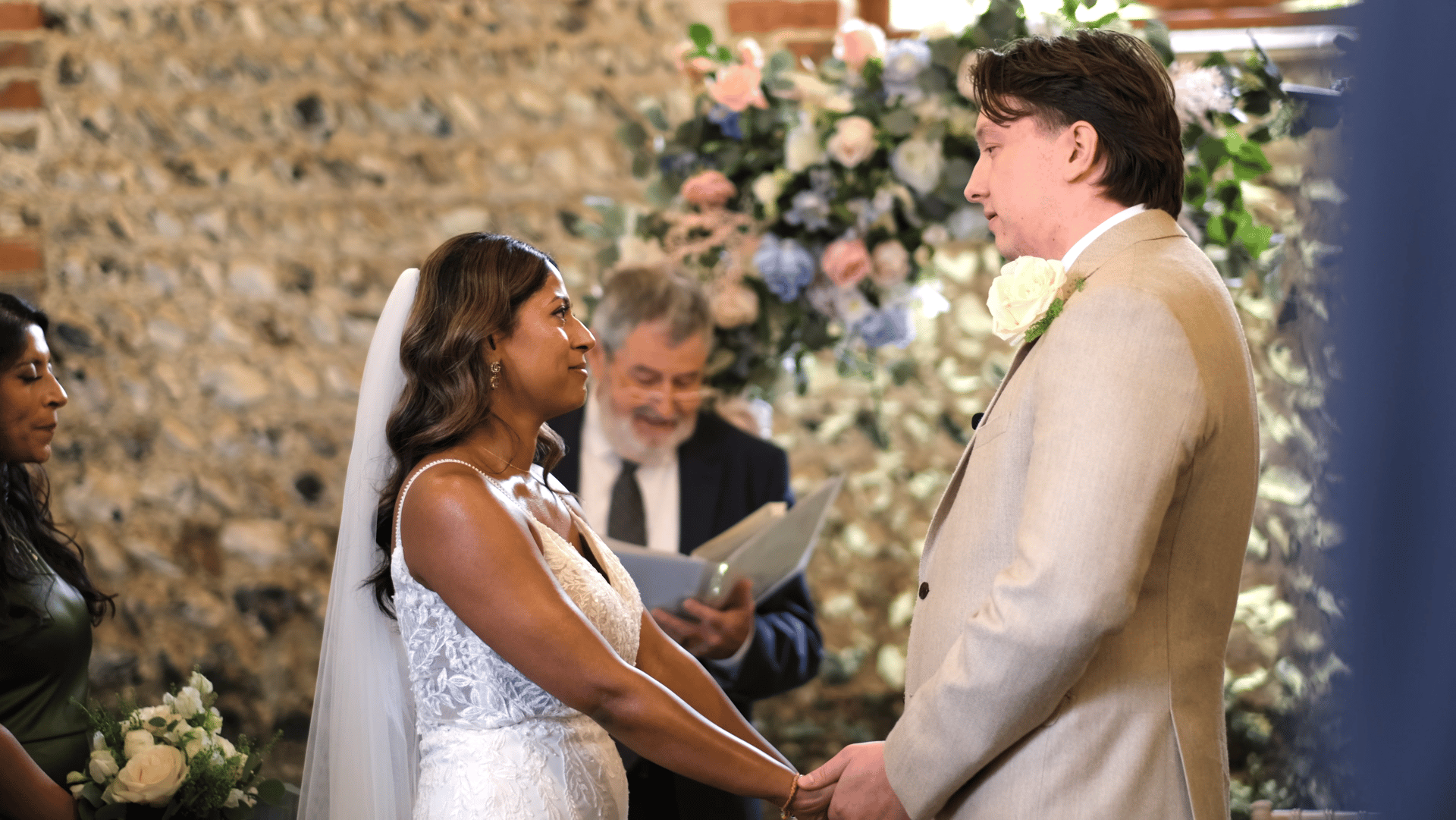 A bride and groom holding hands in a barn