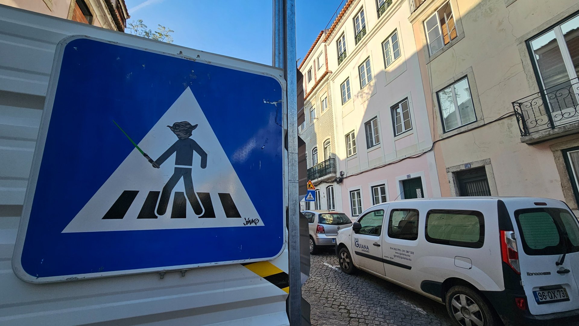 Street art sur panneau de signalisation représentant Yoda sur un panneau piéton à Lisbonne.