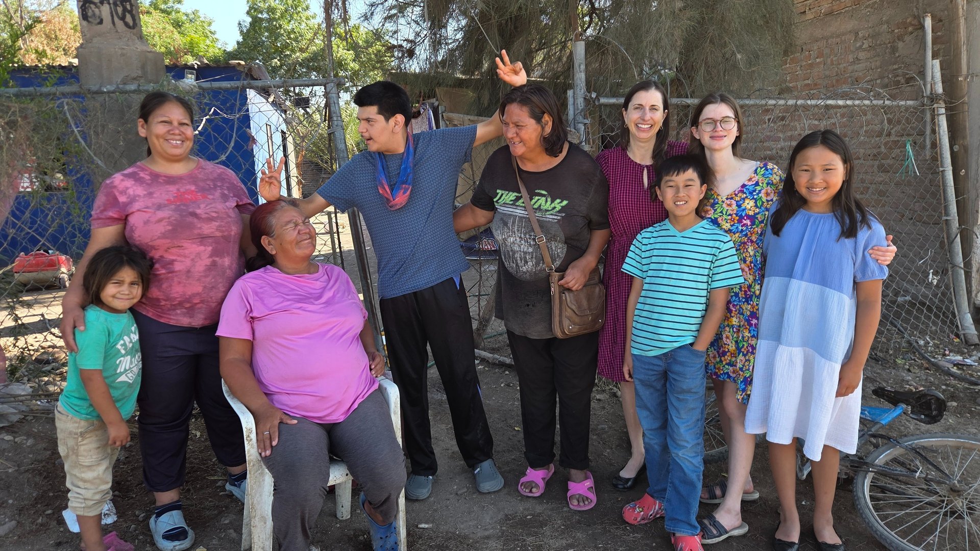 A diverse group of smiling community members and volunteers posing together outdoors.