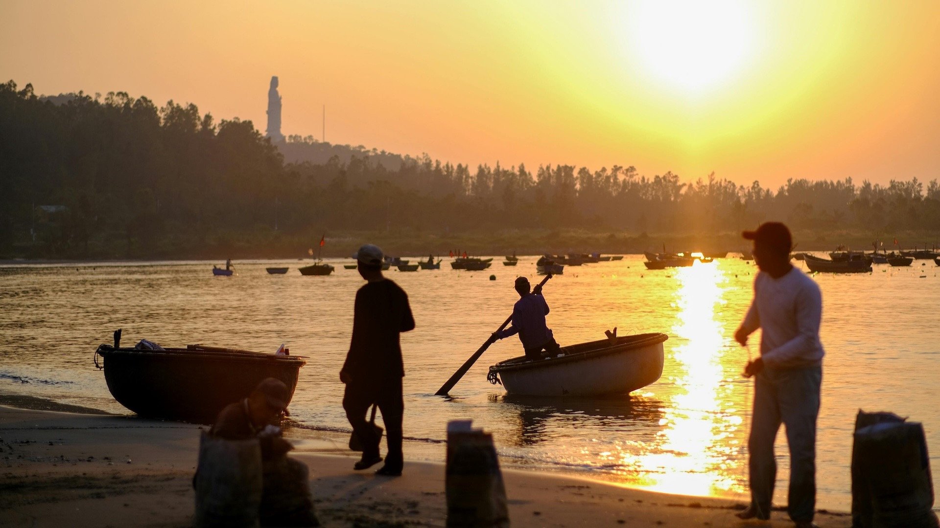 Local fishermen on Da Nang beach at sunrise with basket boat
