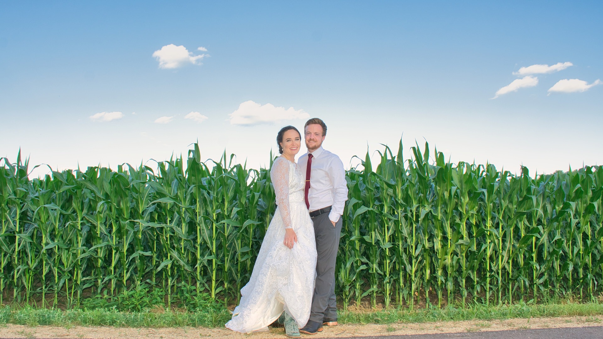 a bride and groom standing in front of a corn field