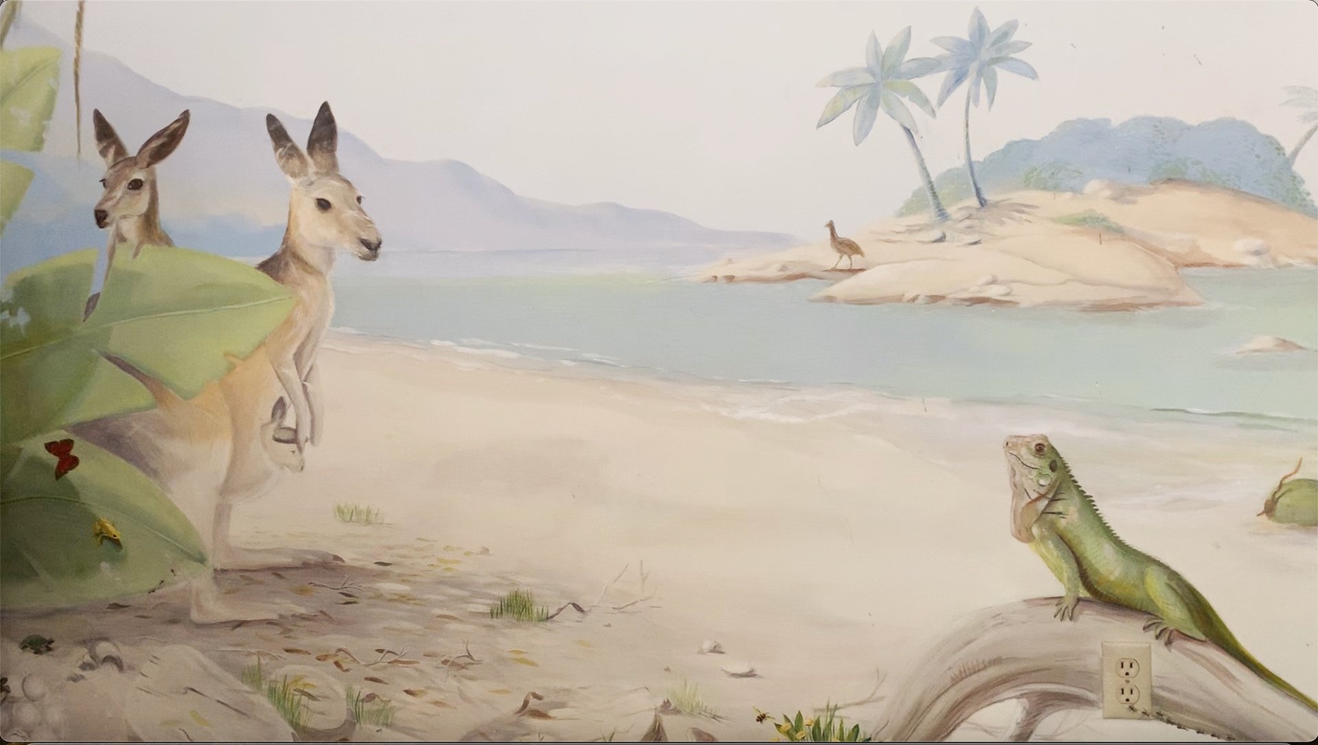 Hand-painted mural scene with kangaroos by the shore and an iguana basking in light—part of an Australian wildlife mural