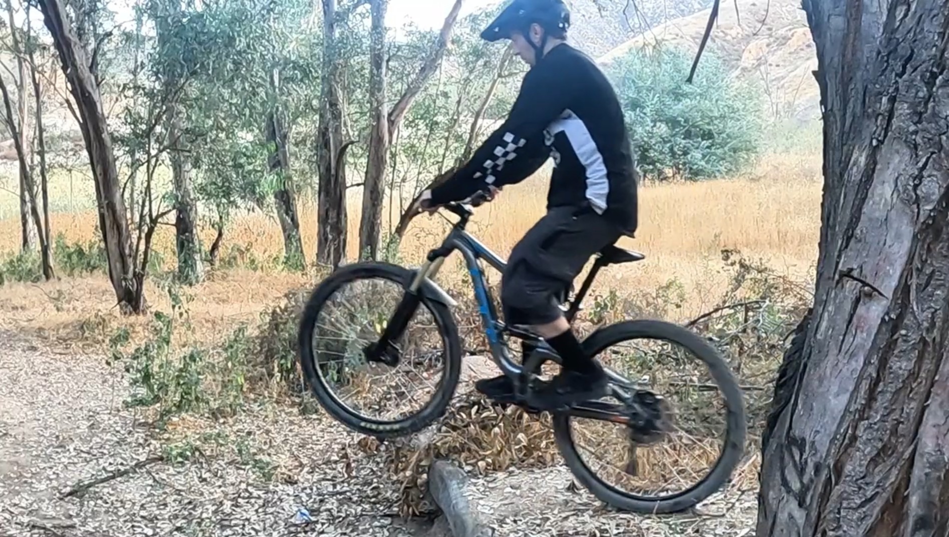 mountain biker approaching small ledge preparing for wheelie drop technique
