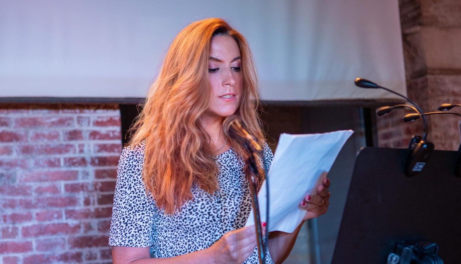 a woman reading a book and holding a microphone
