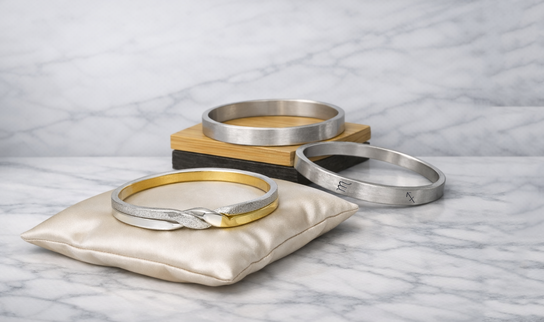 Brushed silver bangles arranged on light marble to show their refined matte finish