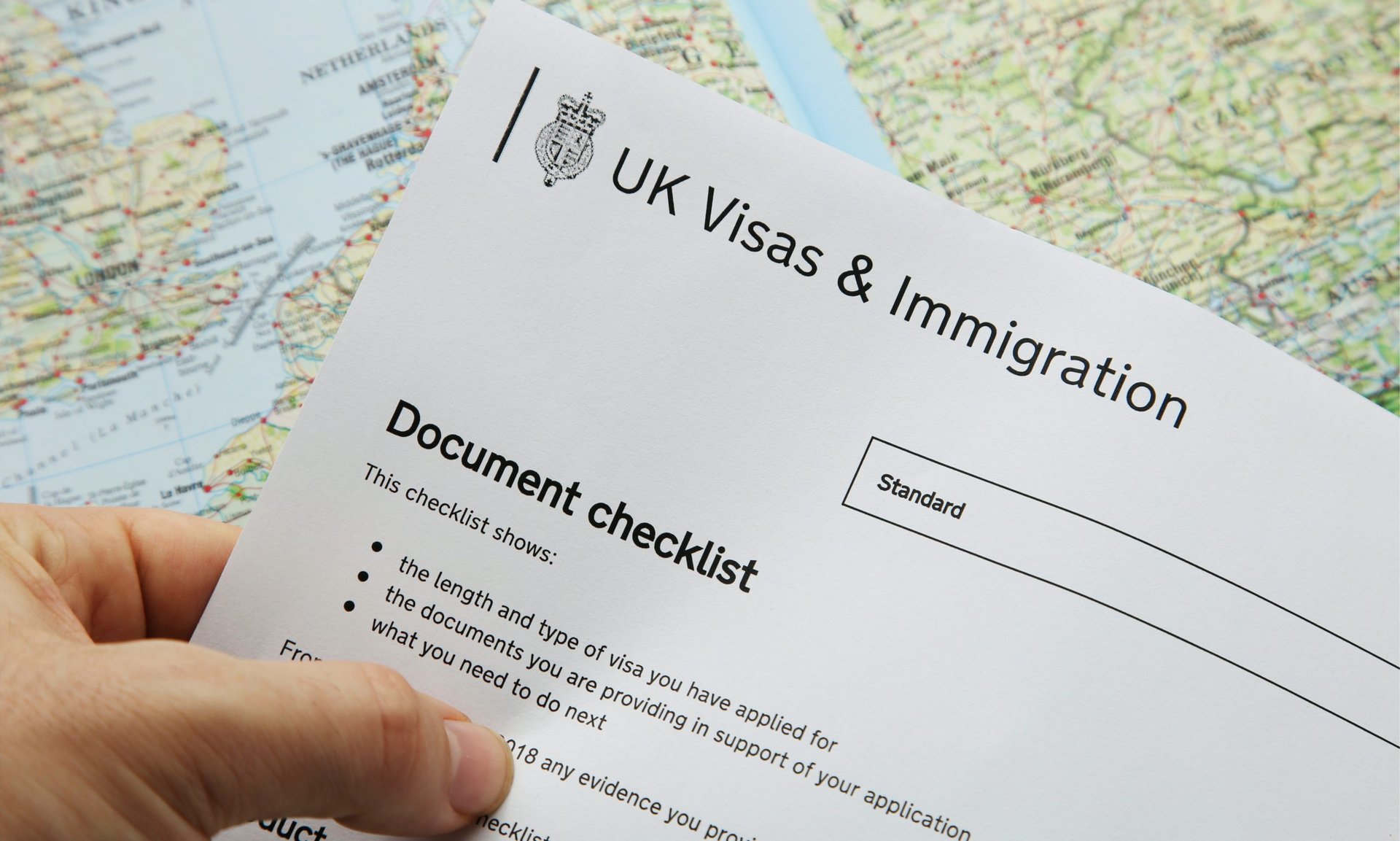Person holding UKVI Document checklist in left hand