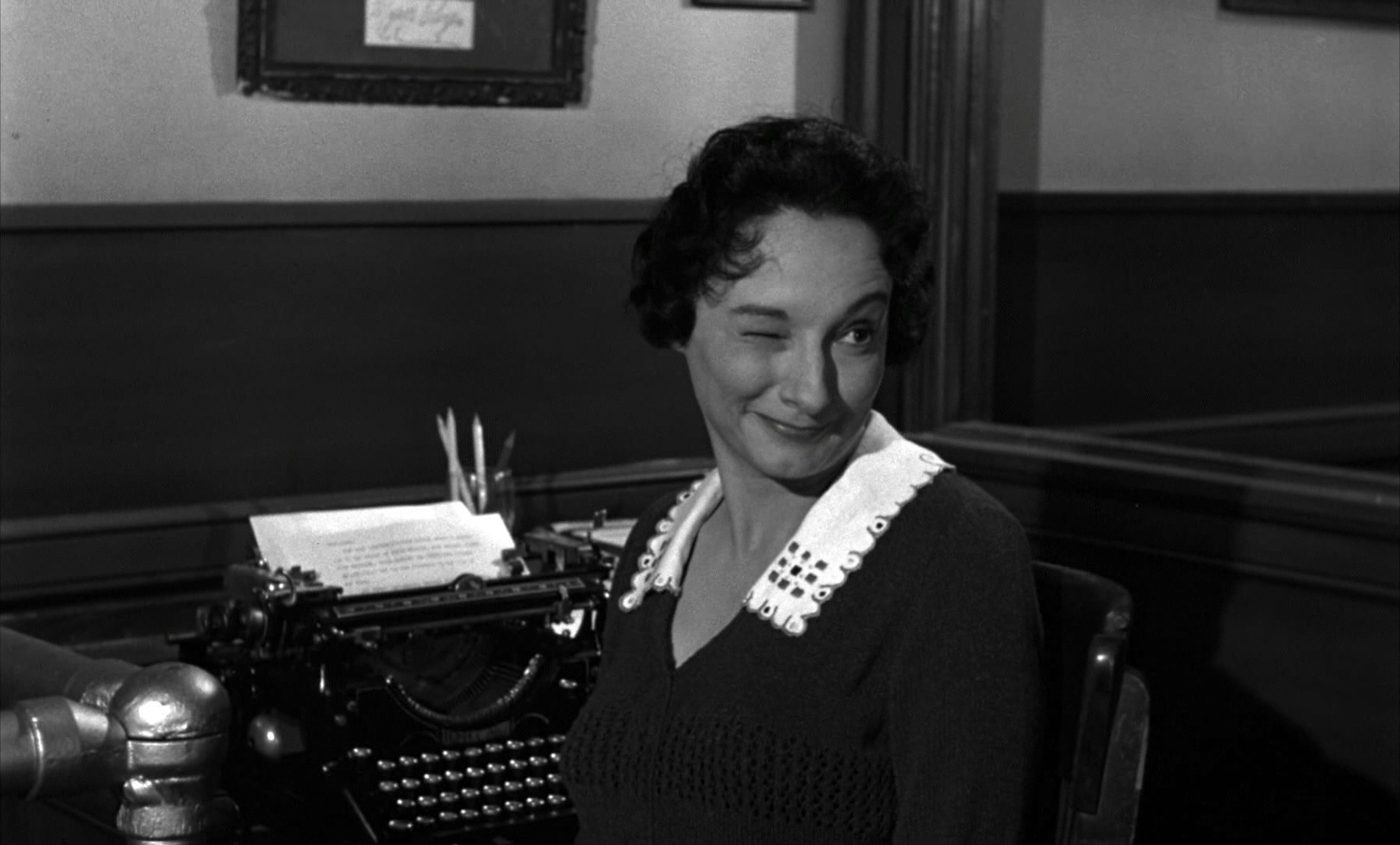 a woman sitting at a desk with a typewriter