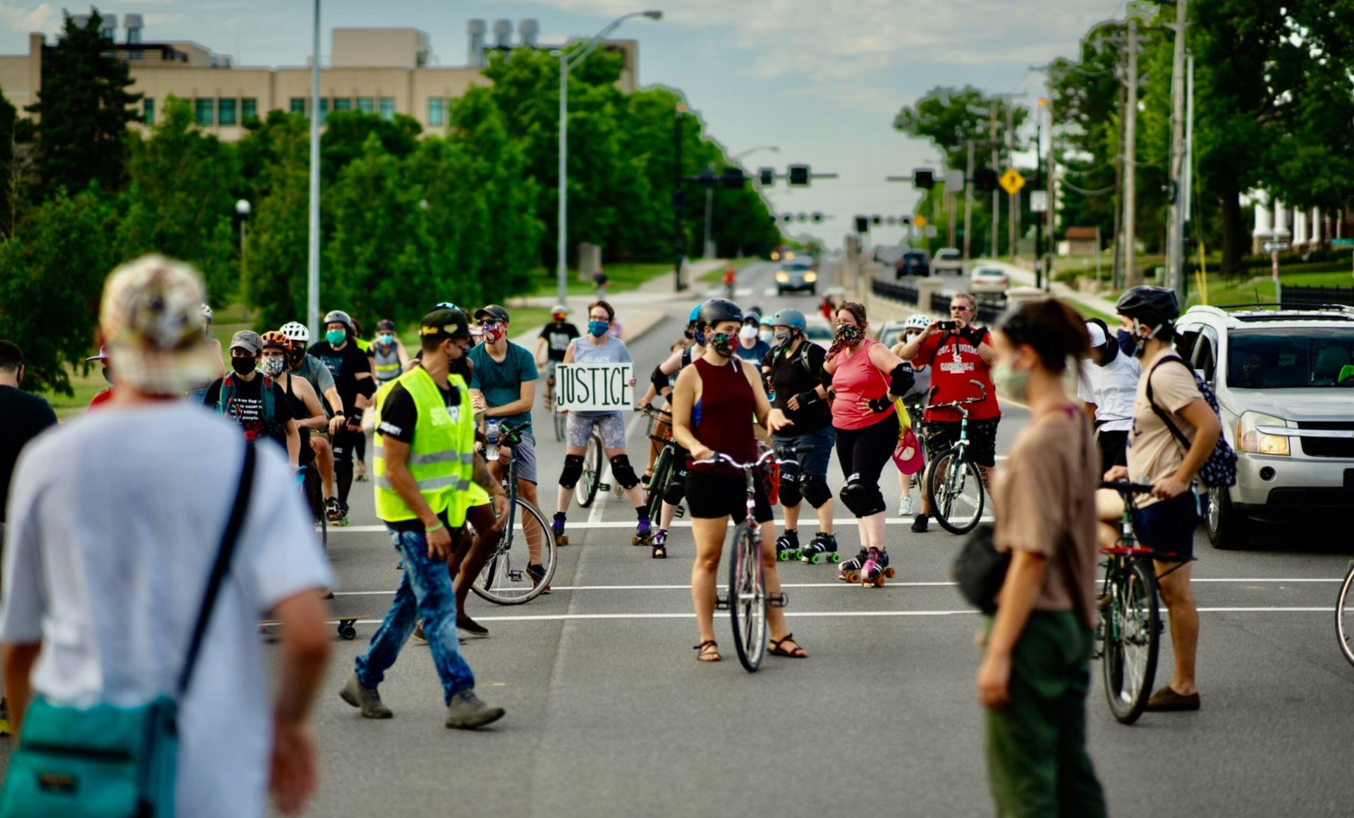 Bikers stopped on a road, with one holding a sign that reads "Justice"