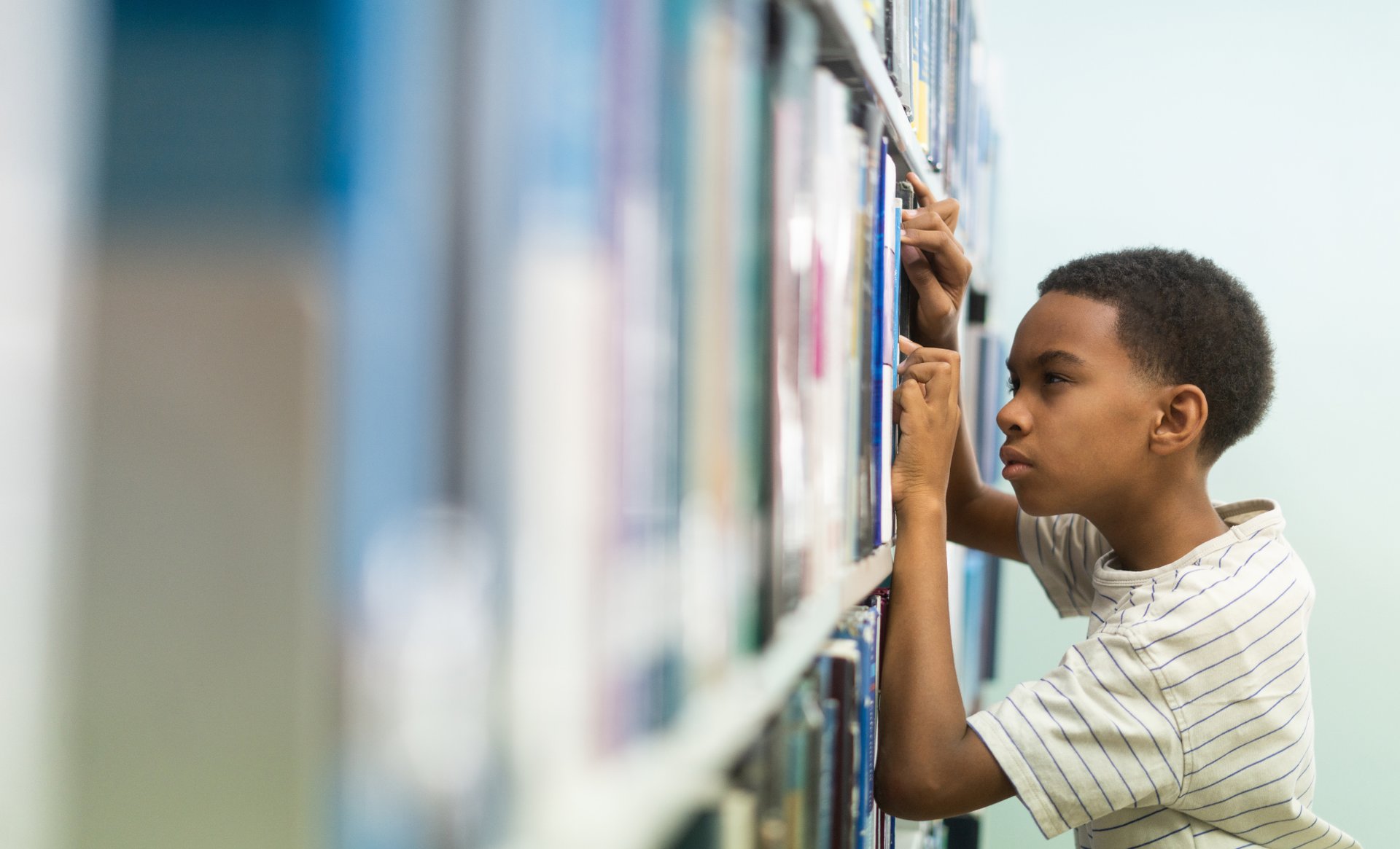 Child with myopia squinting while trying to find a book in the library