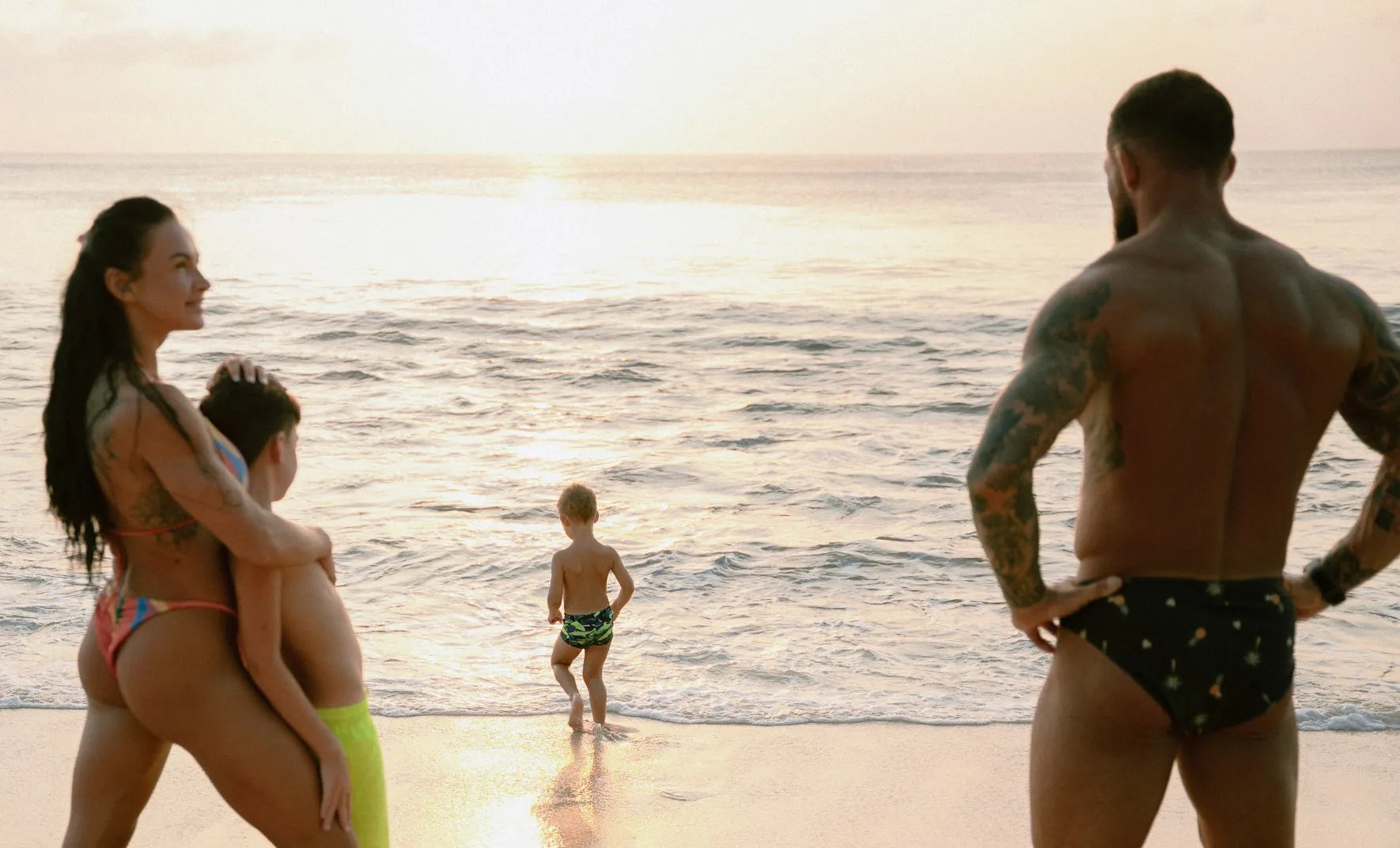 Parents watching their child play near the shoreline during a family photo session at Dreamland Beach Bali.