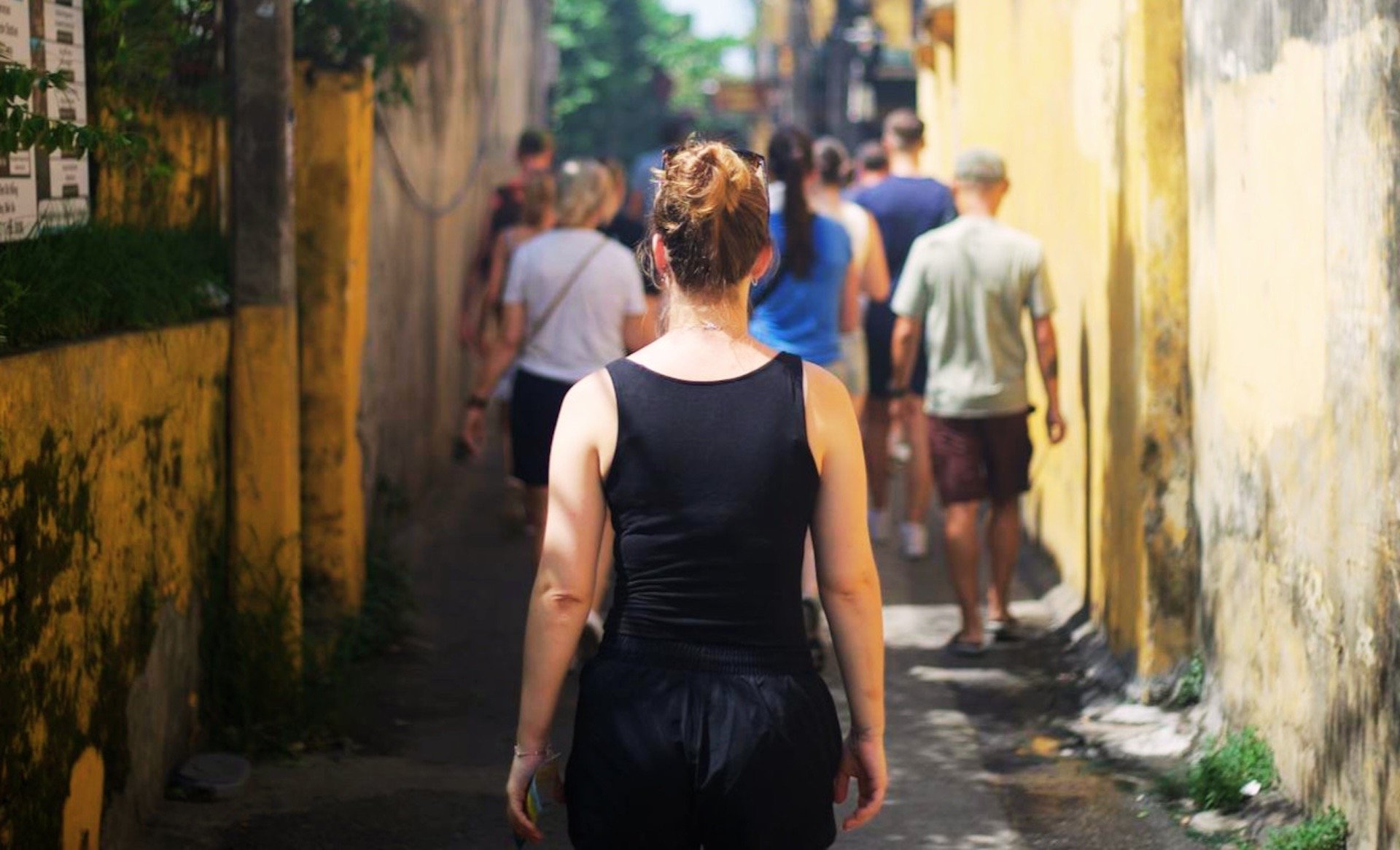 Woman walking down a busy alleyway in Vietnam